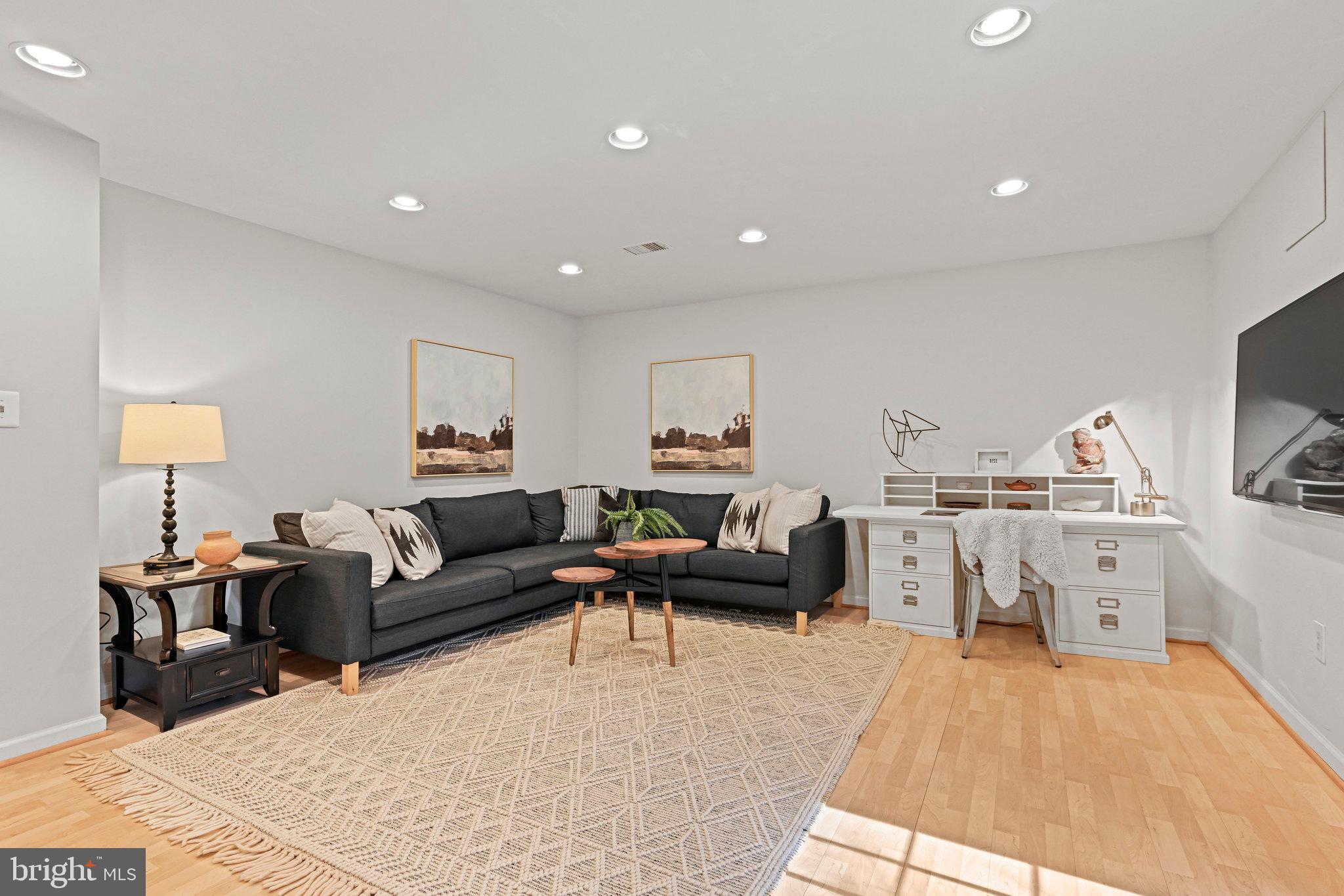 Living room with a dark sectional sofa, patterned rug, and white desk.