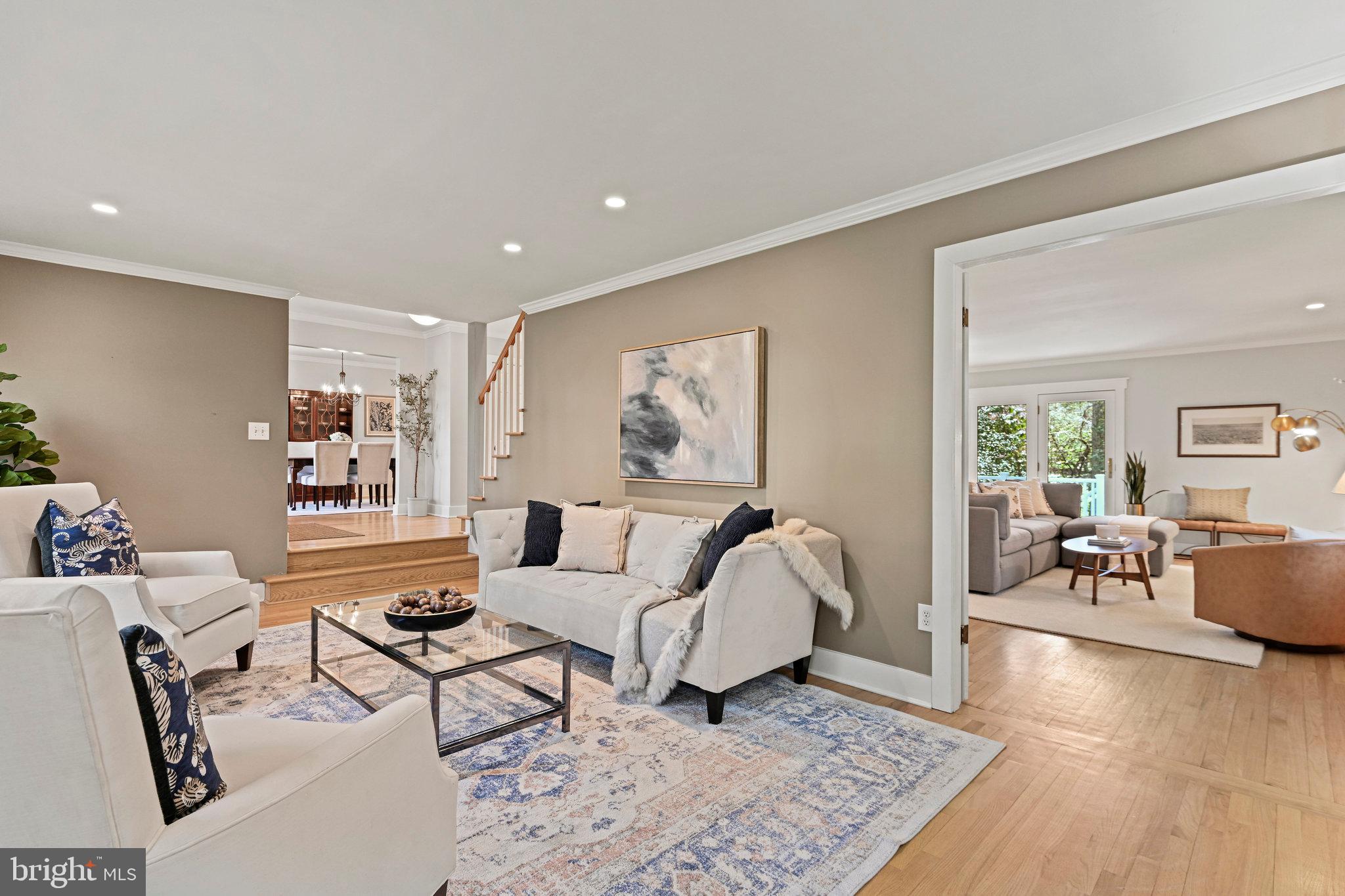 Staged living room with cream sofas, a glass coffee table, and open views into adjoining rooms.