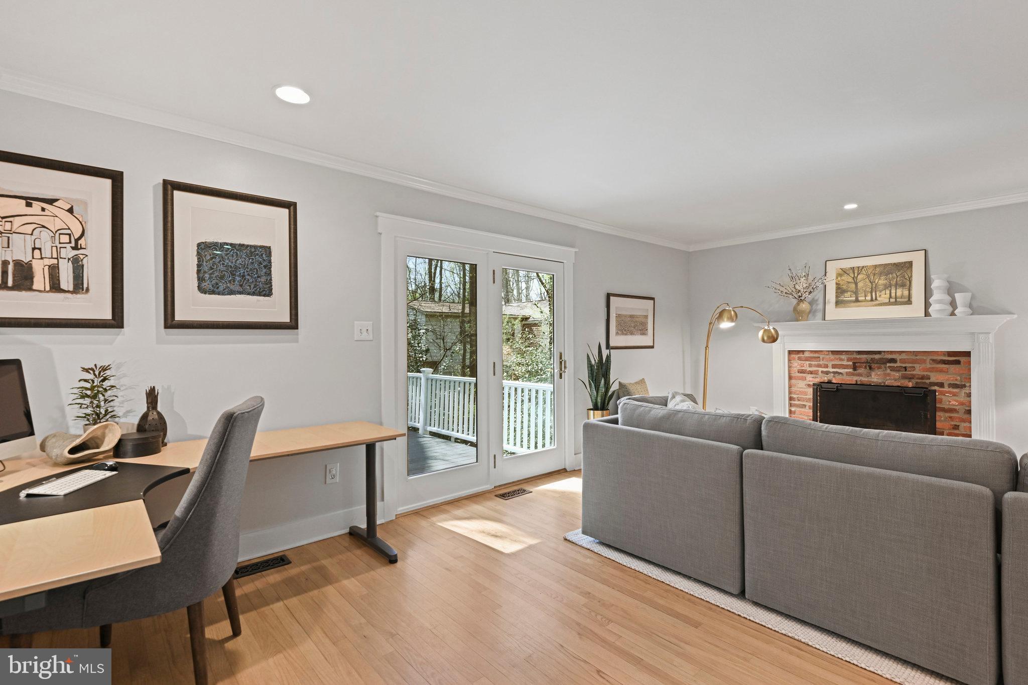 Living room with a gray sectional, brick fireplace, hardwood floors, and glass doors to a deck.