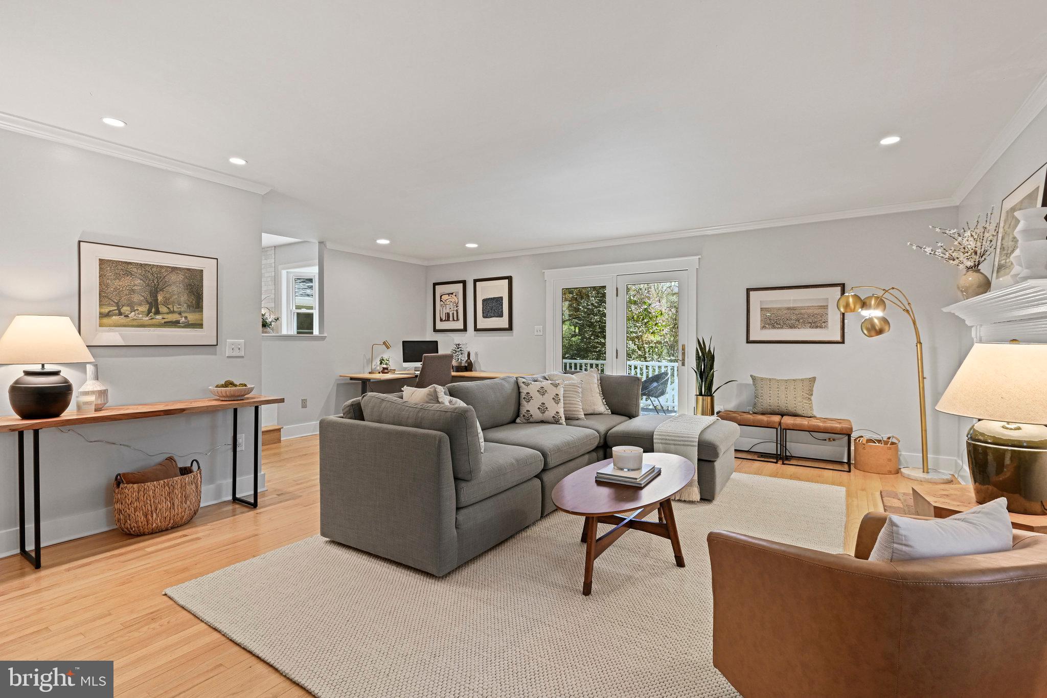 Furnished living room with a gray sectional, wood floors, and glass doors opening to a deck.