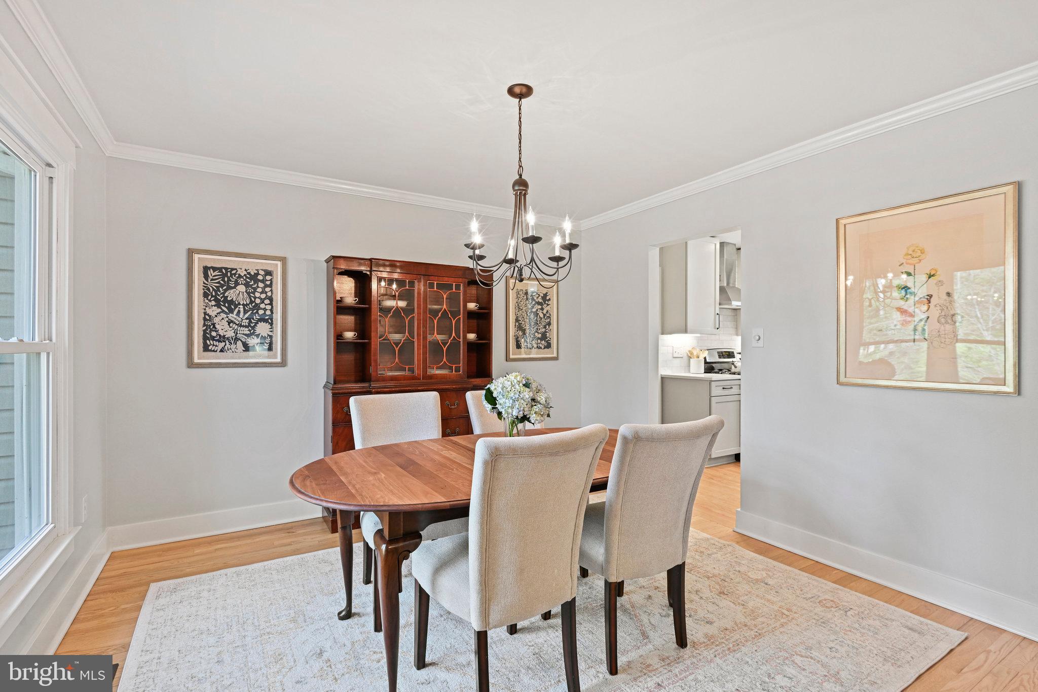 Dining room with a round wooden table, upholstered chairs, and a dark wood china cabinet.
