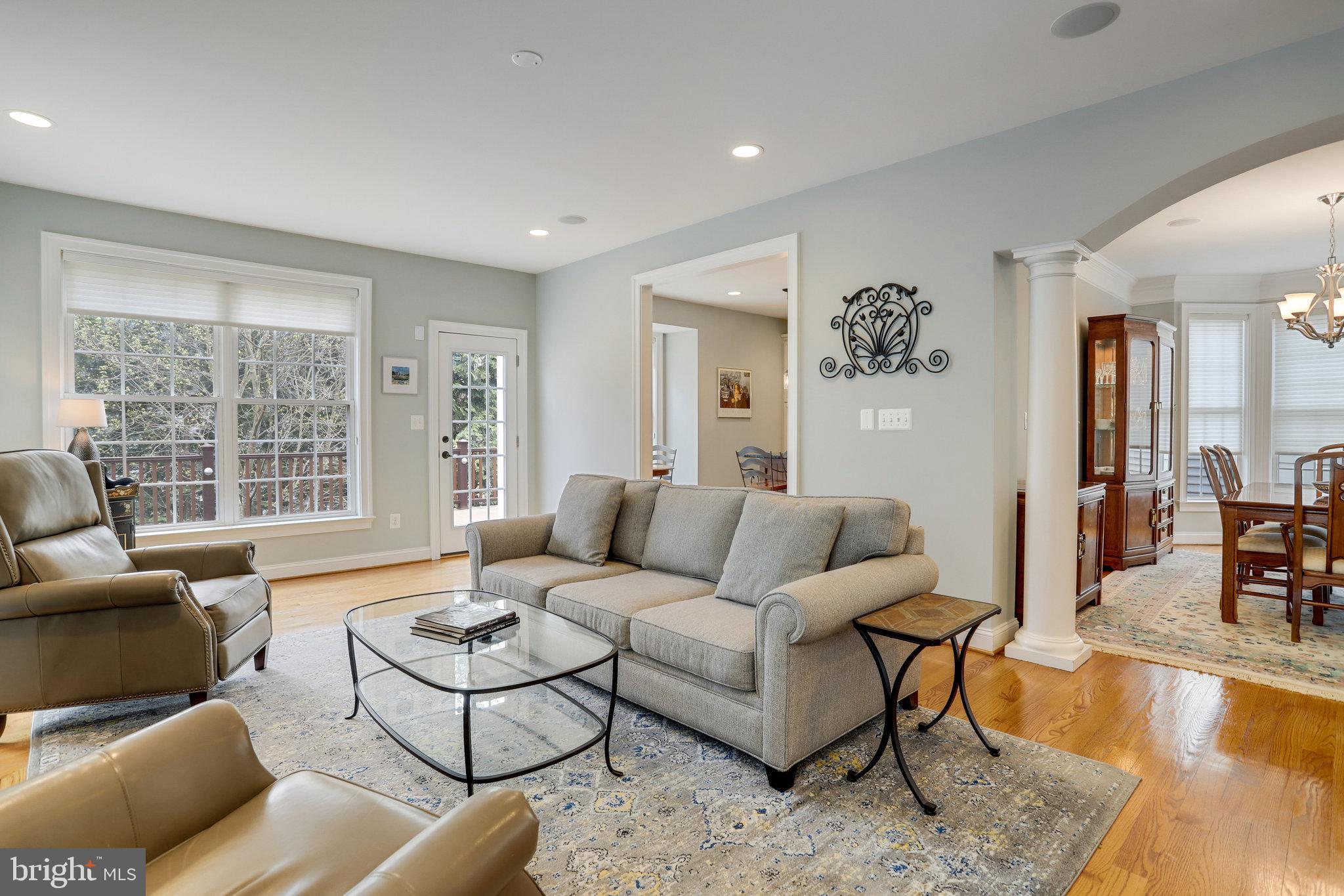 Living room with a gray sofa, leather armchairs, and large windows overlooking a deck.