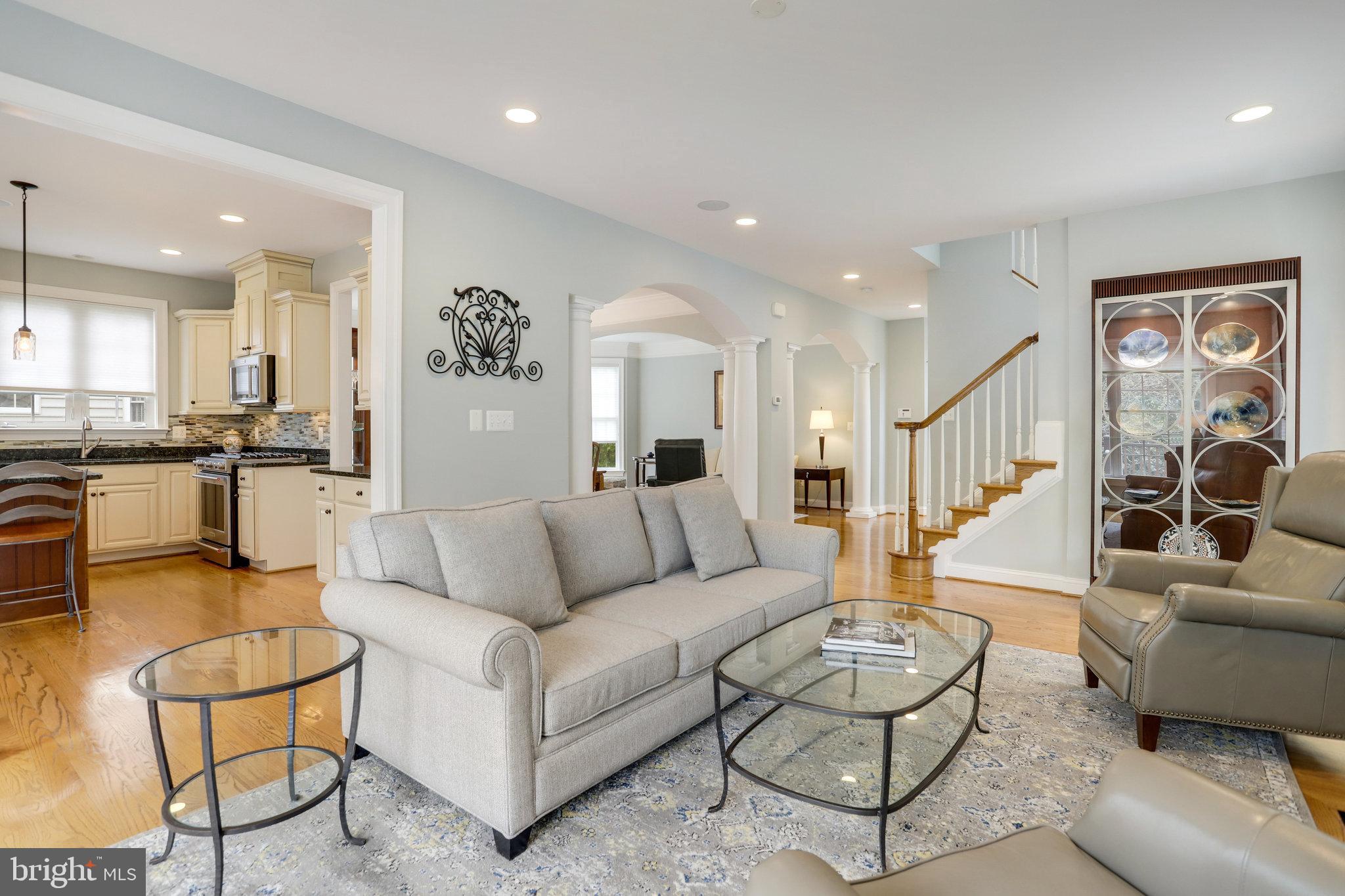Living room with a gray sofa, glass tables, open kitchen, and staircase.