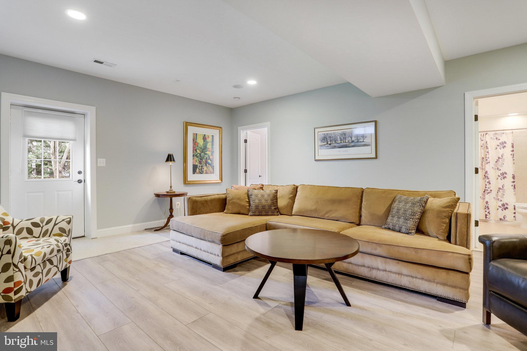 Living room with a tan sectional sofa, round coffee table, and patterned armchair.