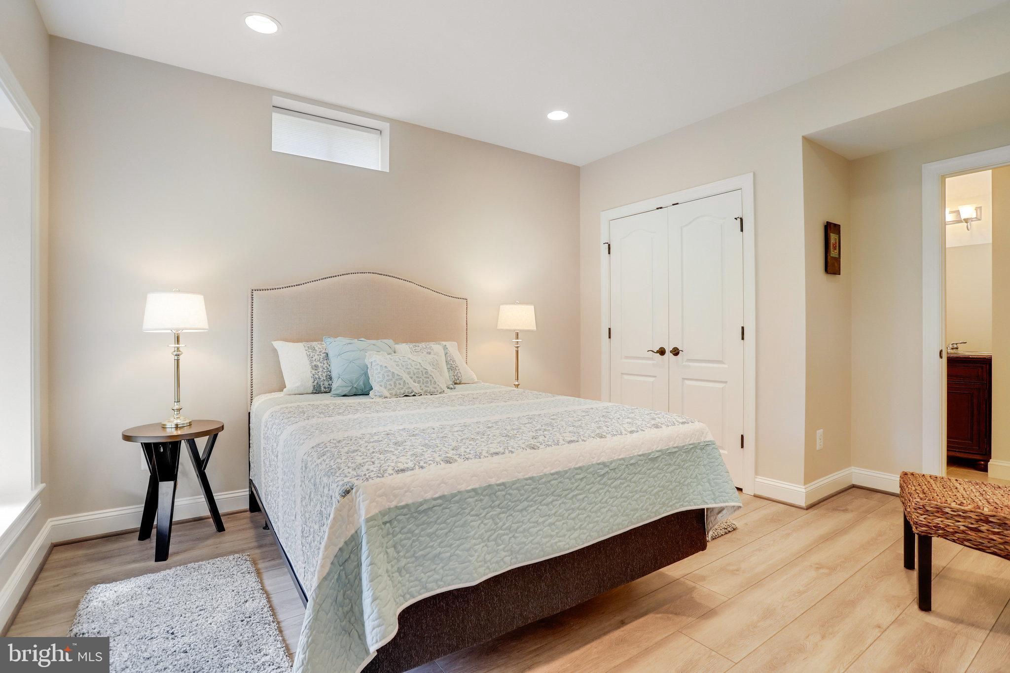 Staged bedroom with pale blue bedding, a tufted headboard, and light wood floors.