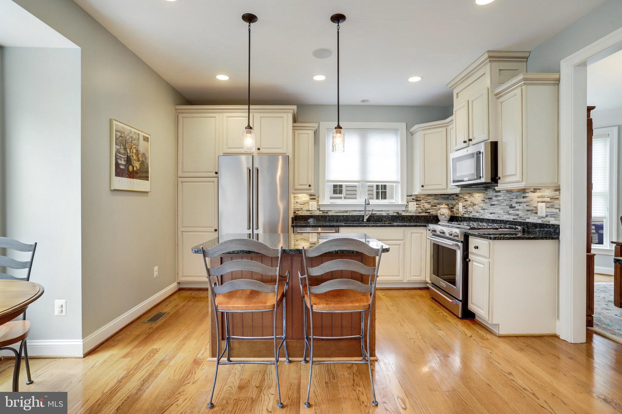 Kitchen with cream cabinets, stainless steel appliances, and a central island with two stools.
