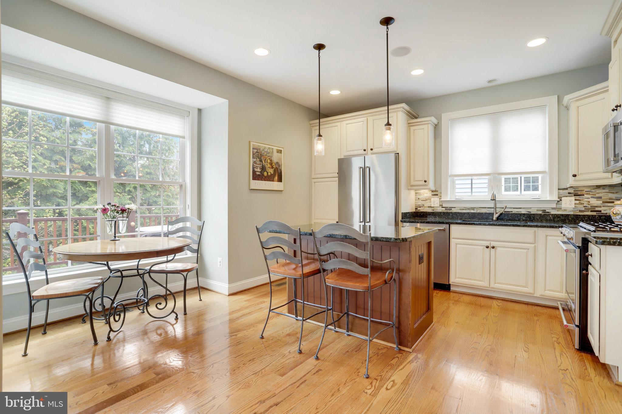 Kitchen with a wood-paneled island and breakfast nook beside large windows.