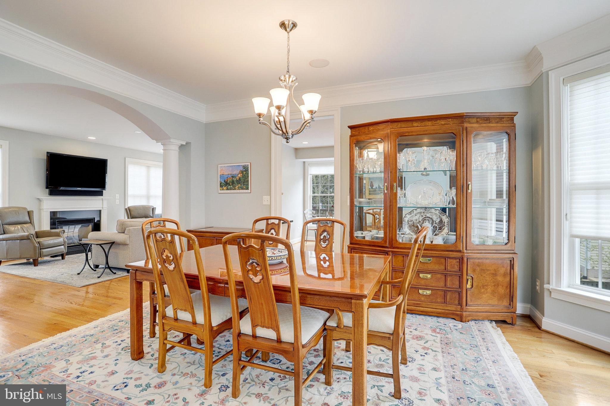 Dining room with a wooden table, glass-front china cabinet, chandelier, and archway to the living room.
