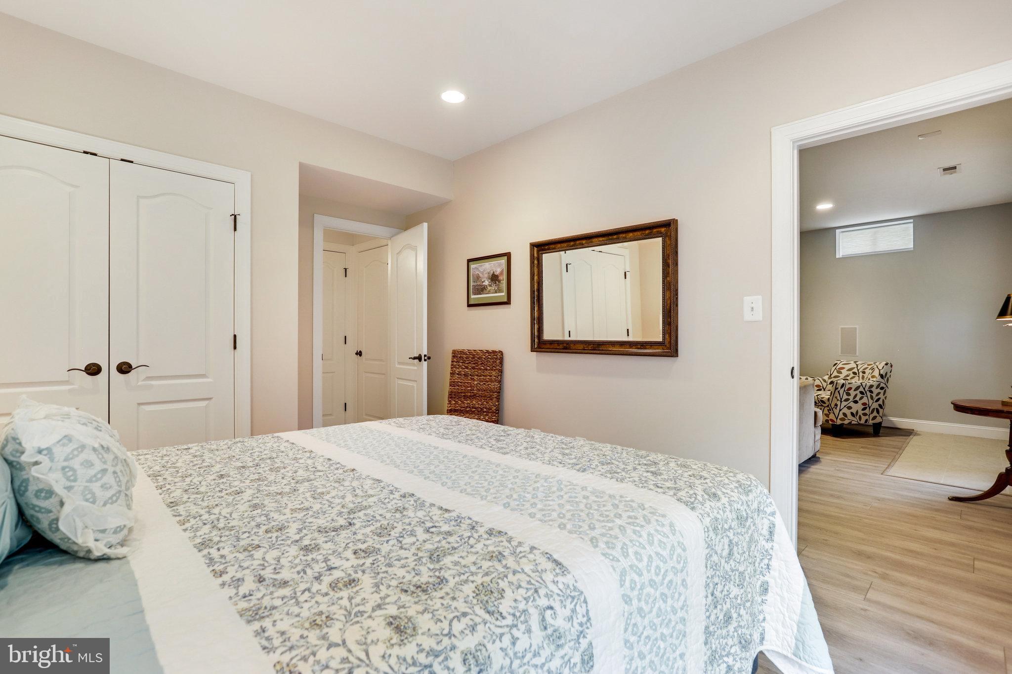Bedroom with a patterned bedspread, white closet doors, and a doorway to a sitting area.