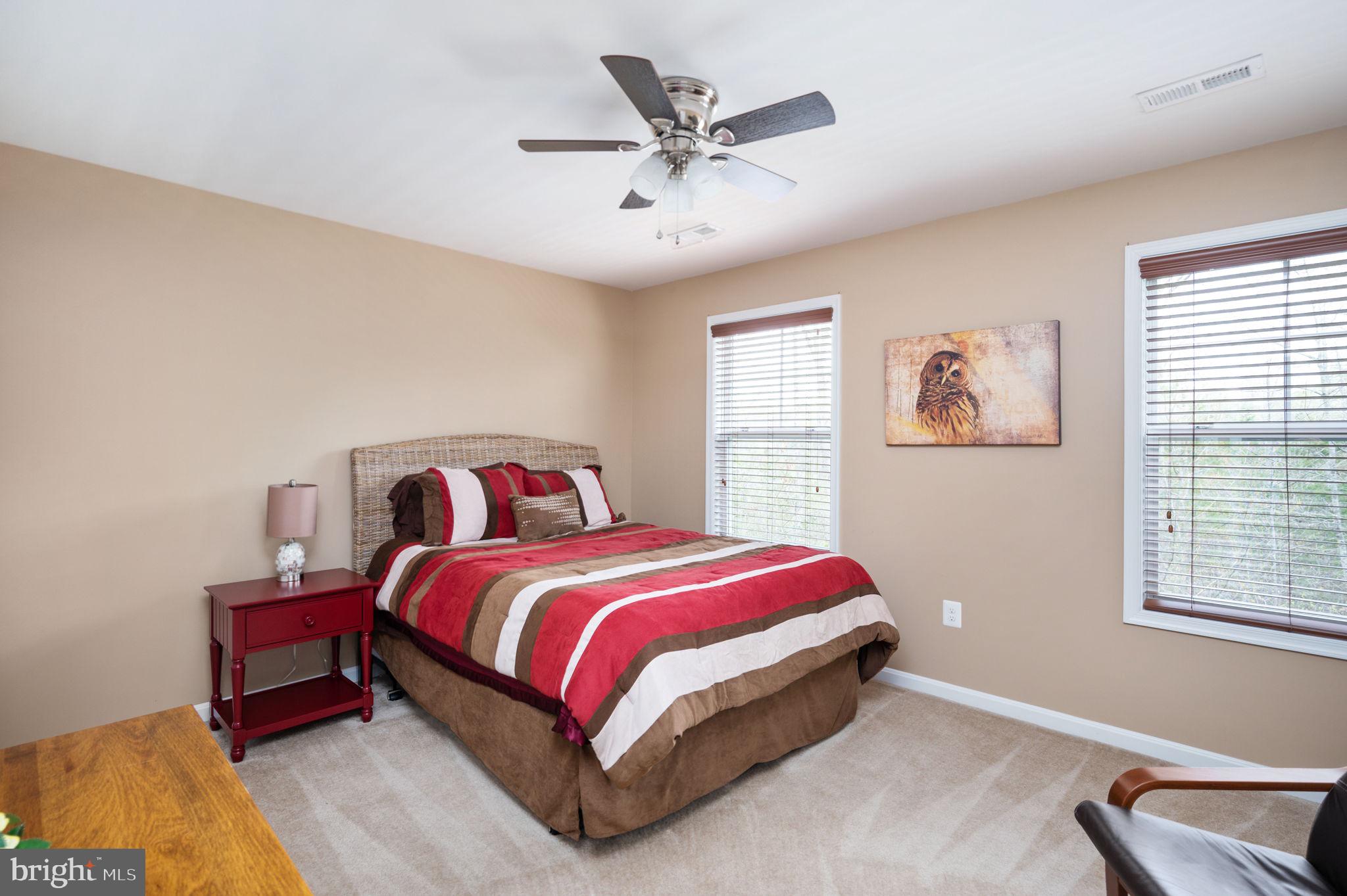 Furnished bedroom with red striped bedding, a red bedside table, and owl wall art.