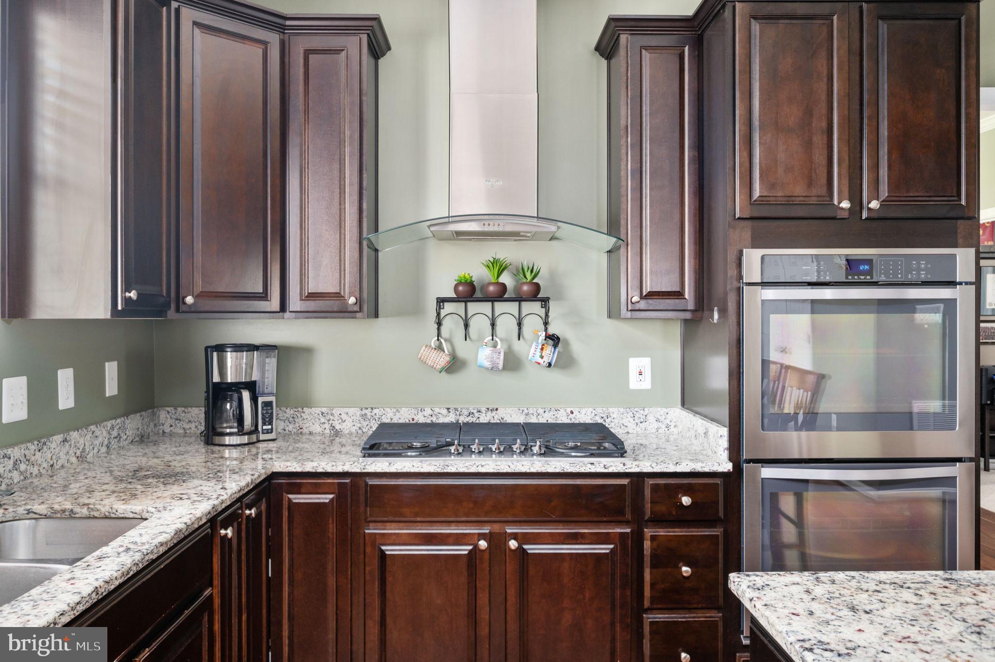 Kitchen with cherry cabinets, granite counters, a gas cooktop, and stainless steel double oven.