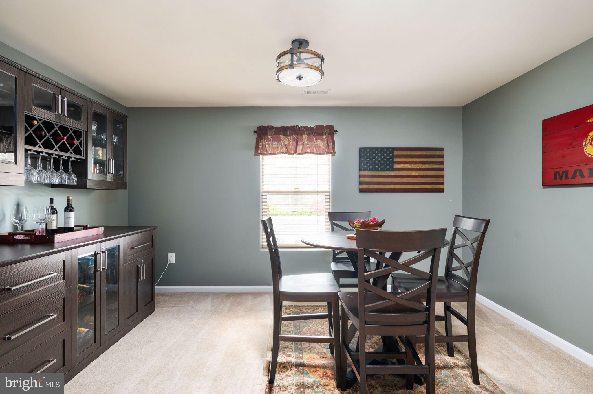Dining room with a dark built-in bar cabinet, round table, and wooden American flag.