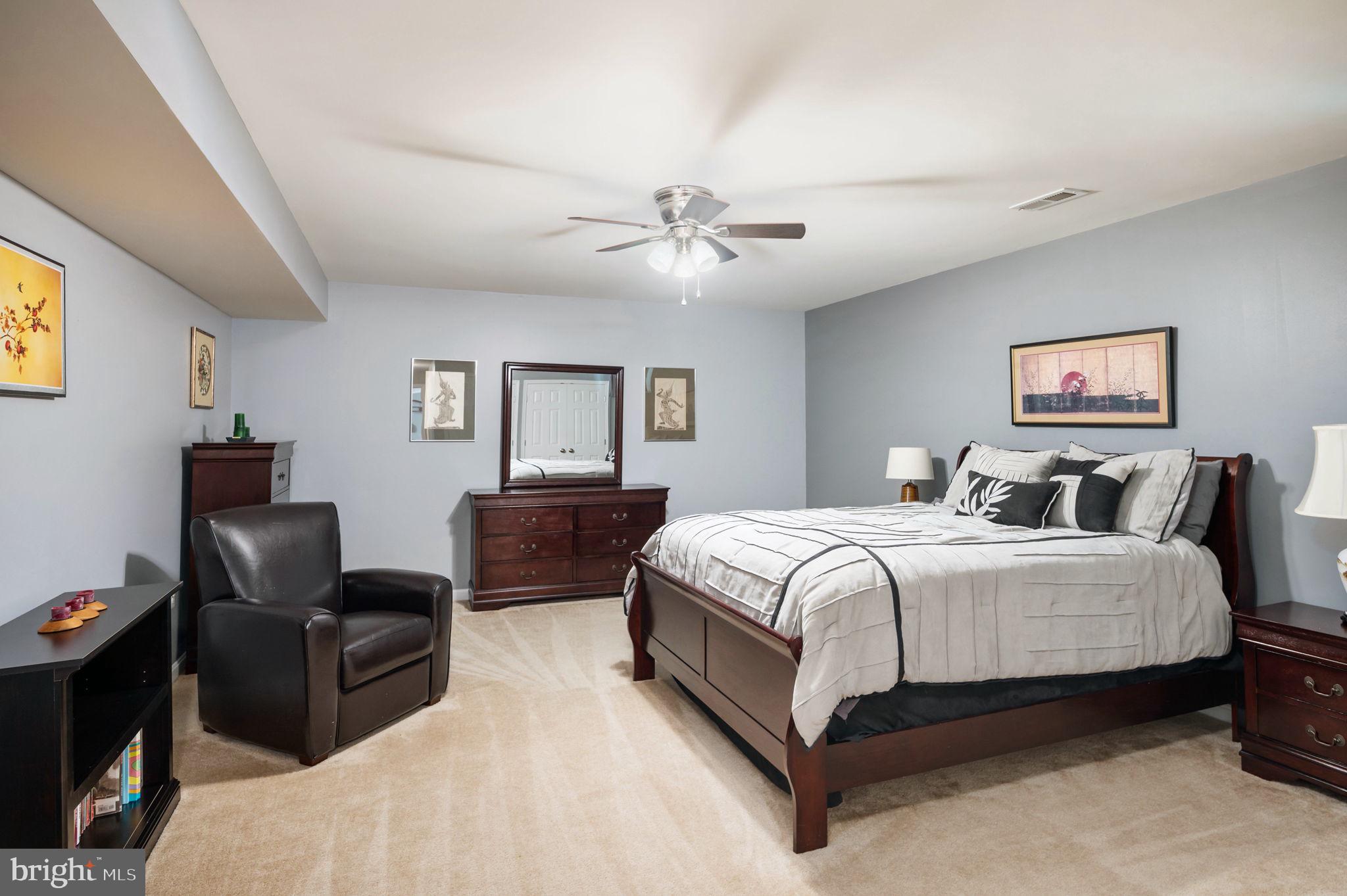 Furnished bedroom with a dark wood bed, matching dresser, and leather armchair.