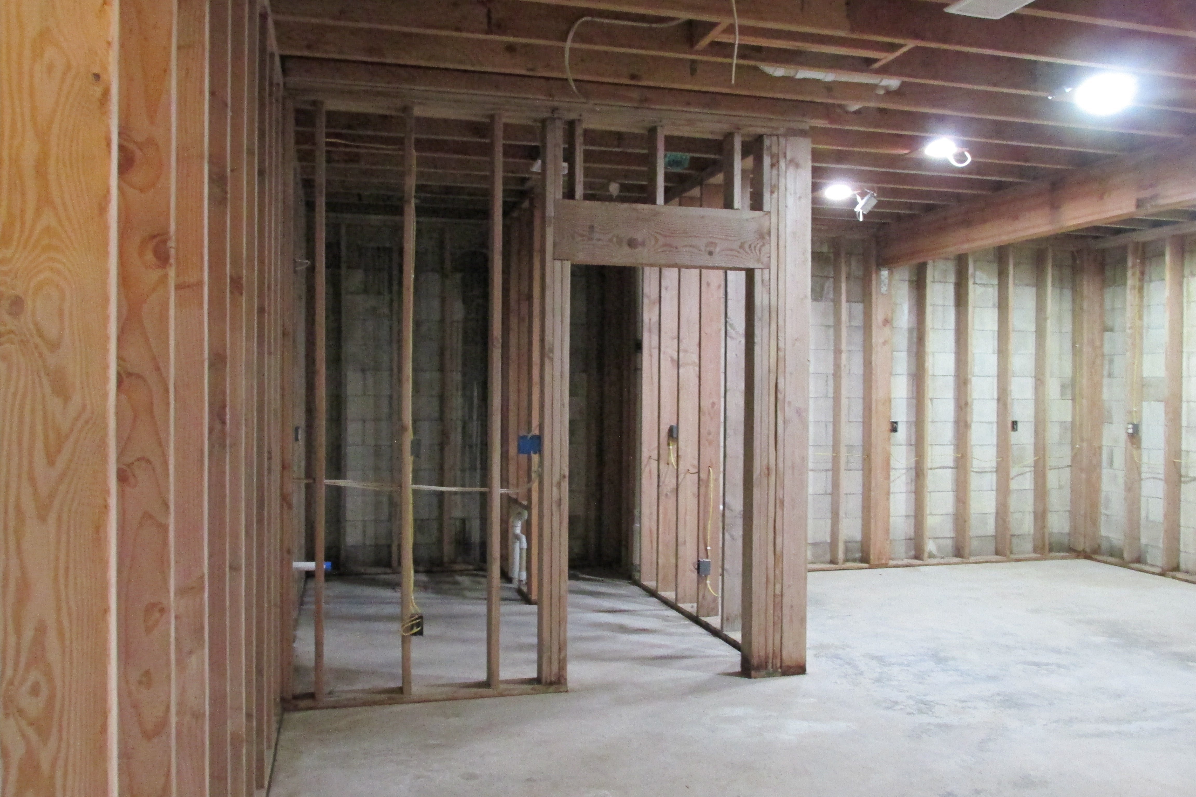 Unfinished interior with exposed framing, concrete block walls, and a bare concrete floor.