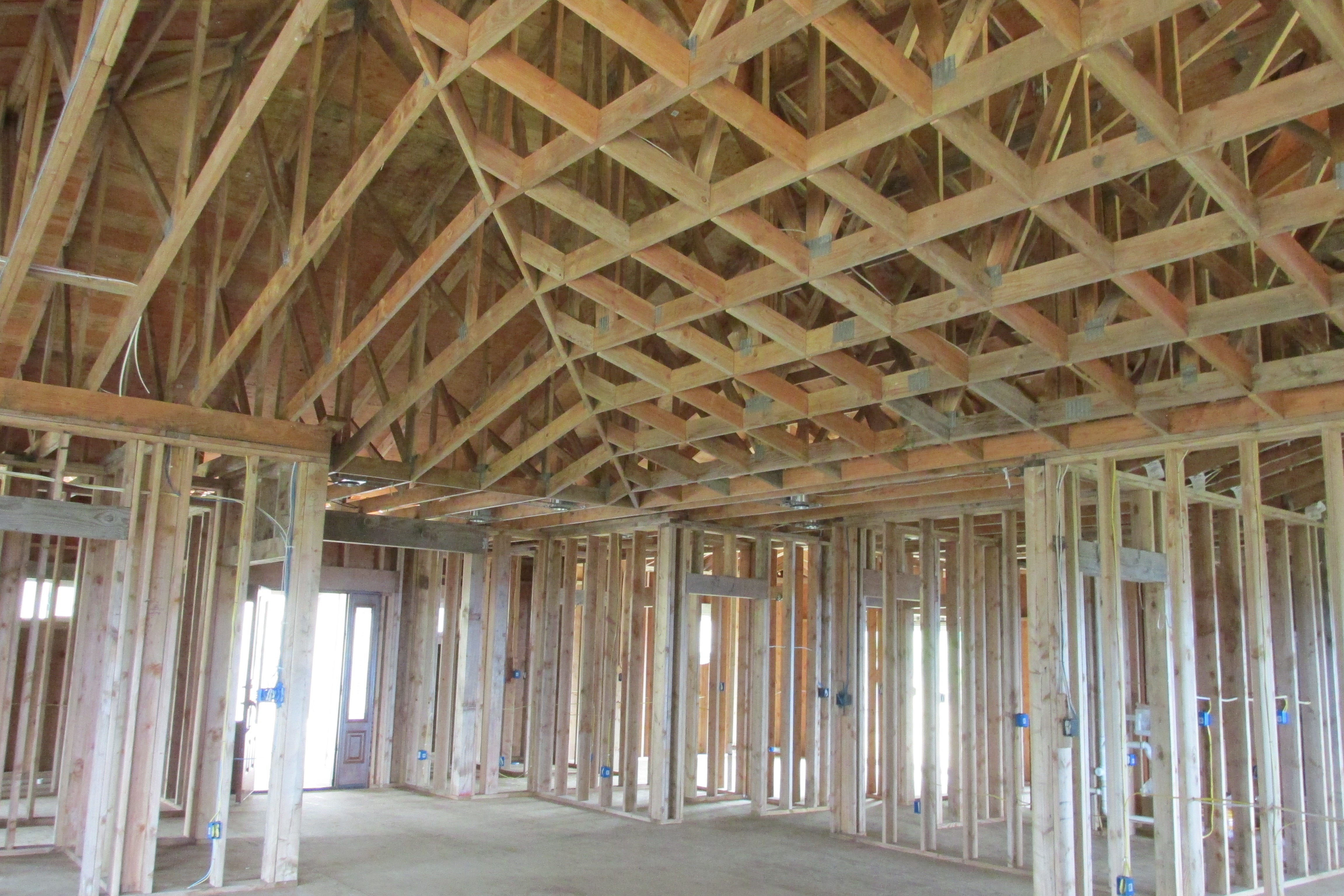 Unfinished home interior with exposed timber framing and extensive roof trusses.