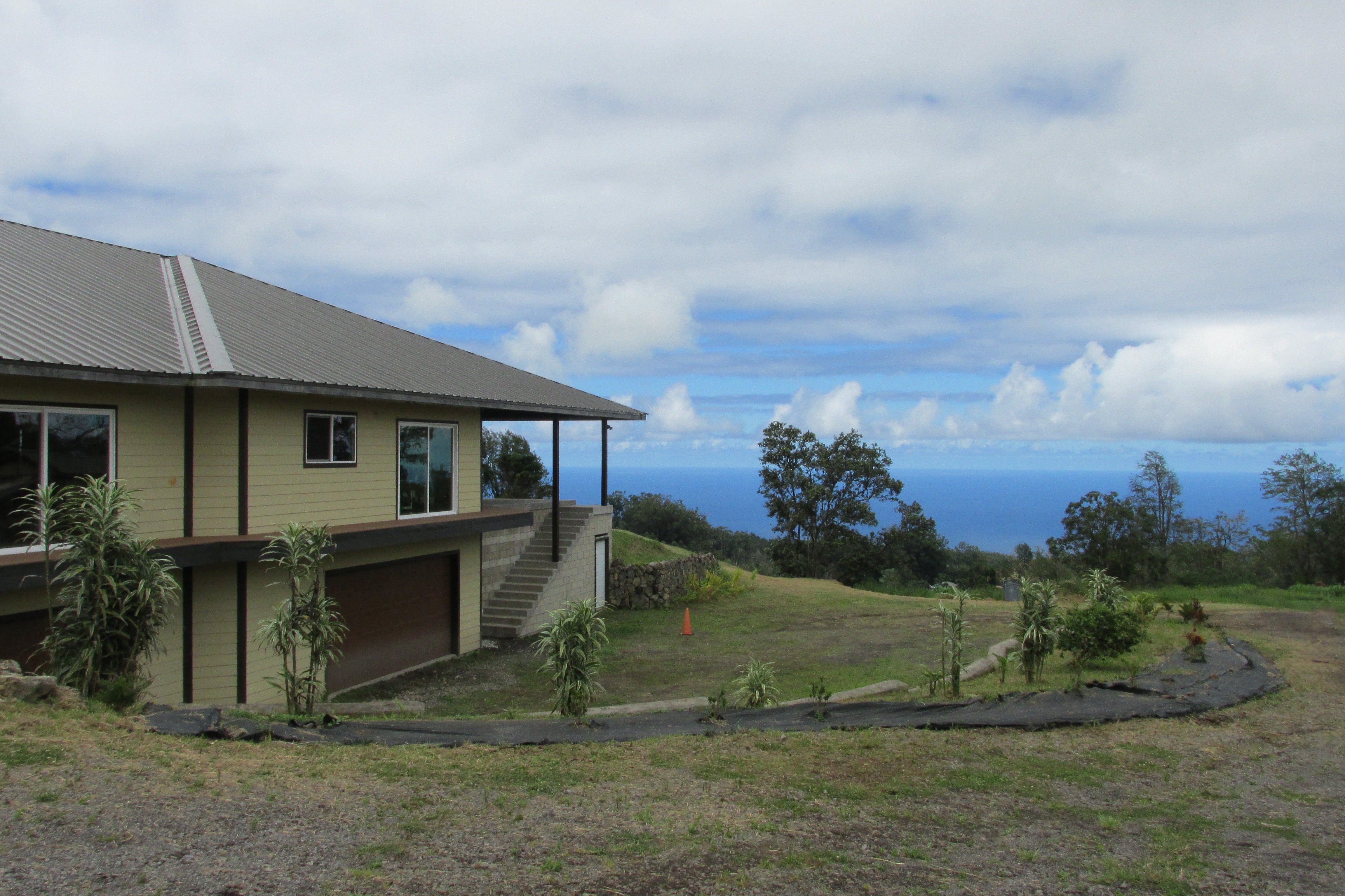 Hillside home with a metal roof and garage overlooking the ocean.