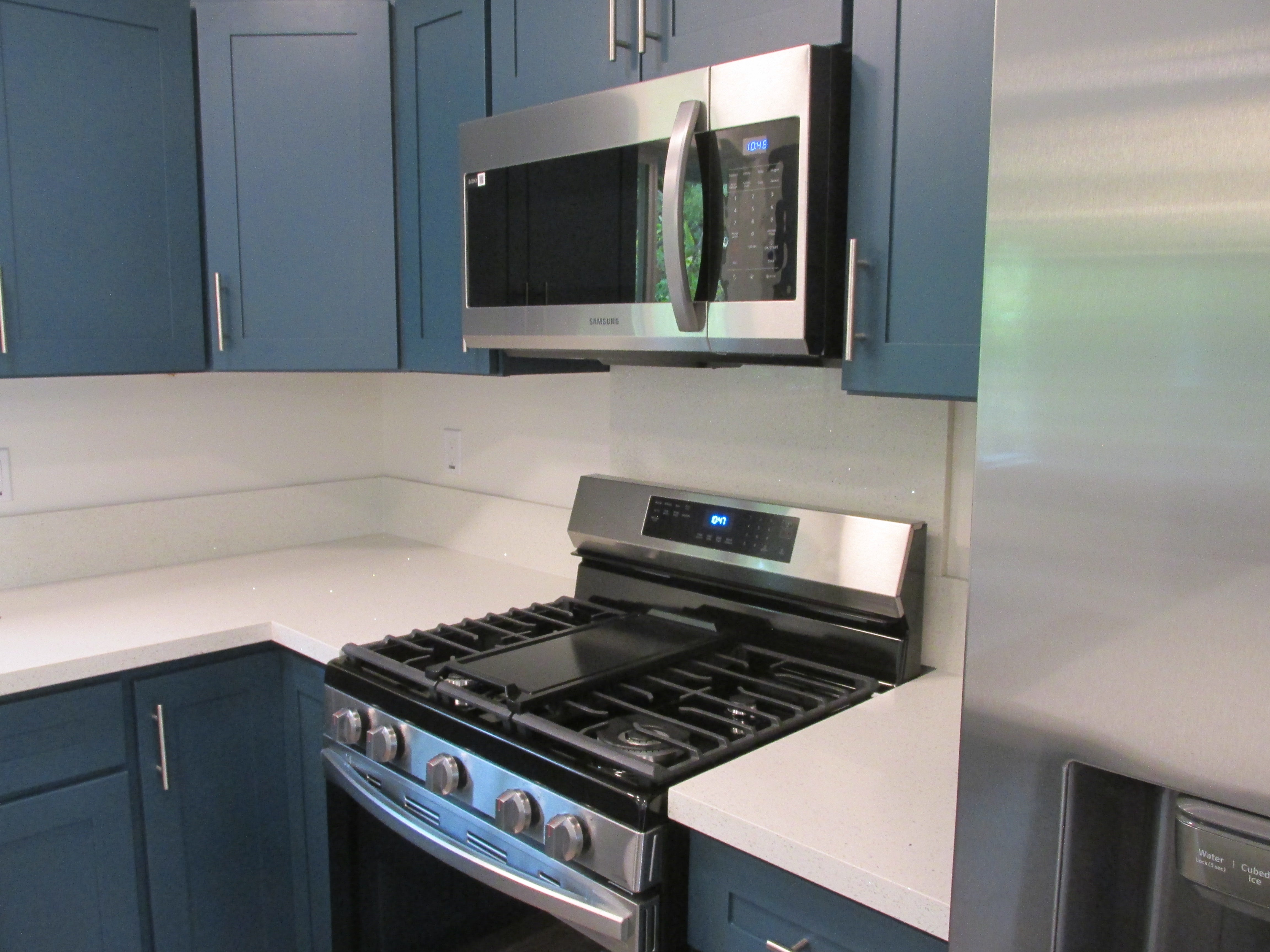 Kitchen with blue cabinets, white countertops, a stainless steel gas range, and built-in microwave.