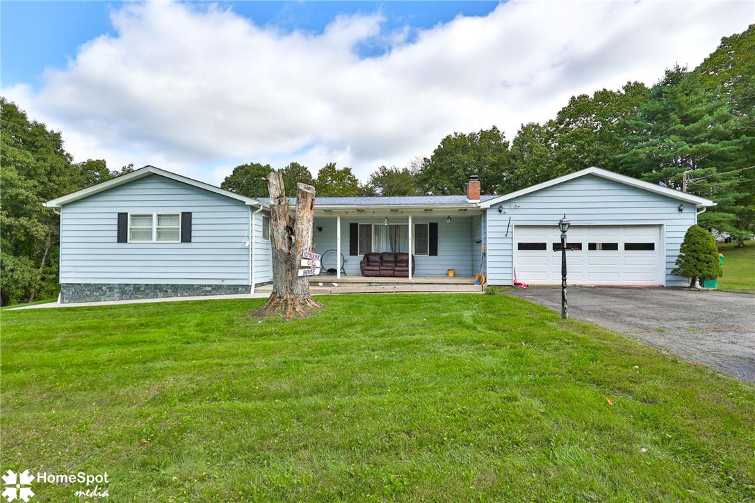 Light-blue ranch home with an attached two-car garage and covered porch, seen across a broad green lawn.