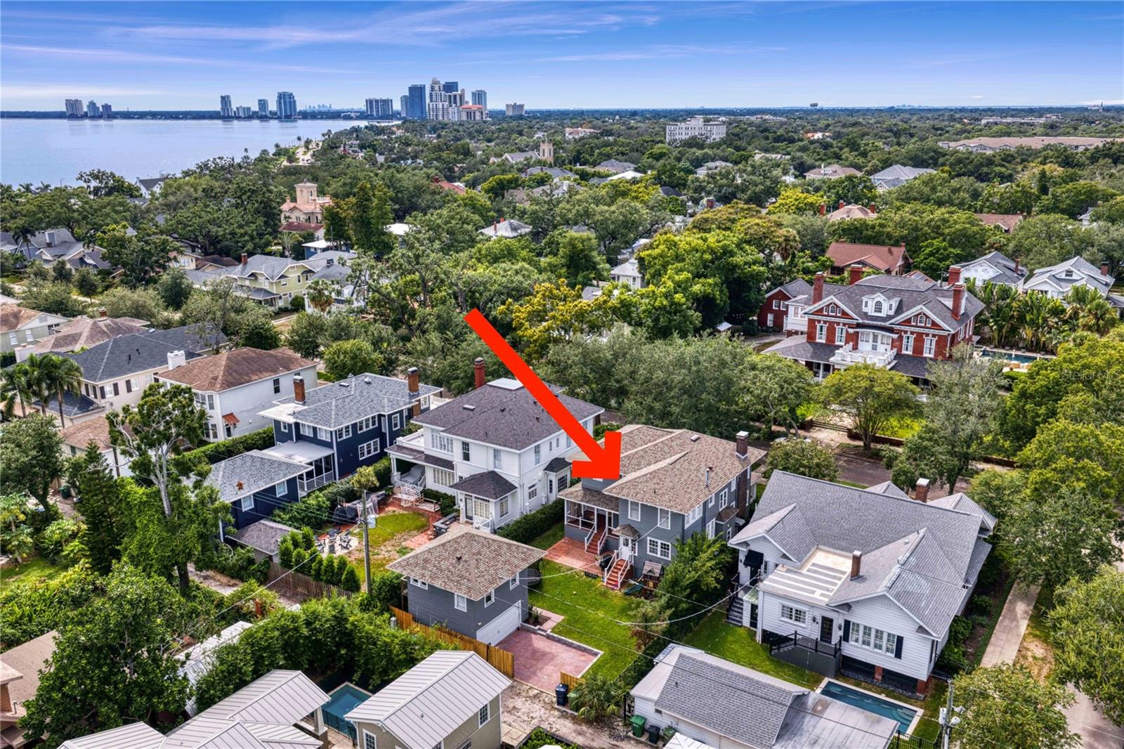 Aerial view of the arrow-marked Tampa home, with the bay and city skyline in the distance.