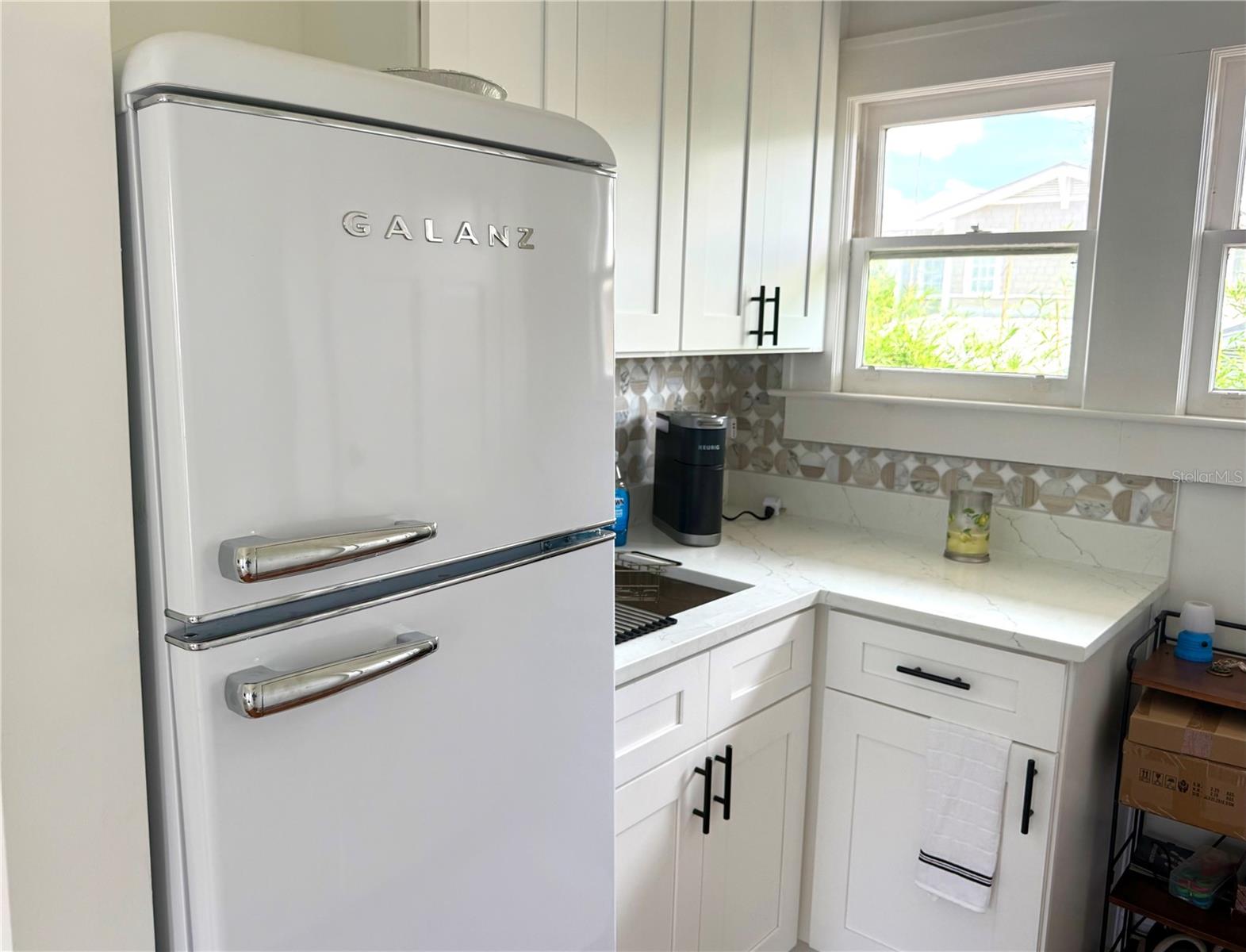 Kitchen with a white retro-style refrigerator, marble-look counters, and patterned backsplash.