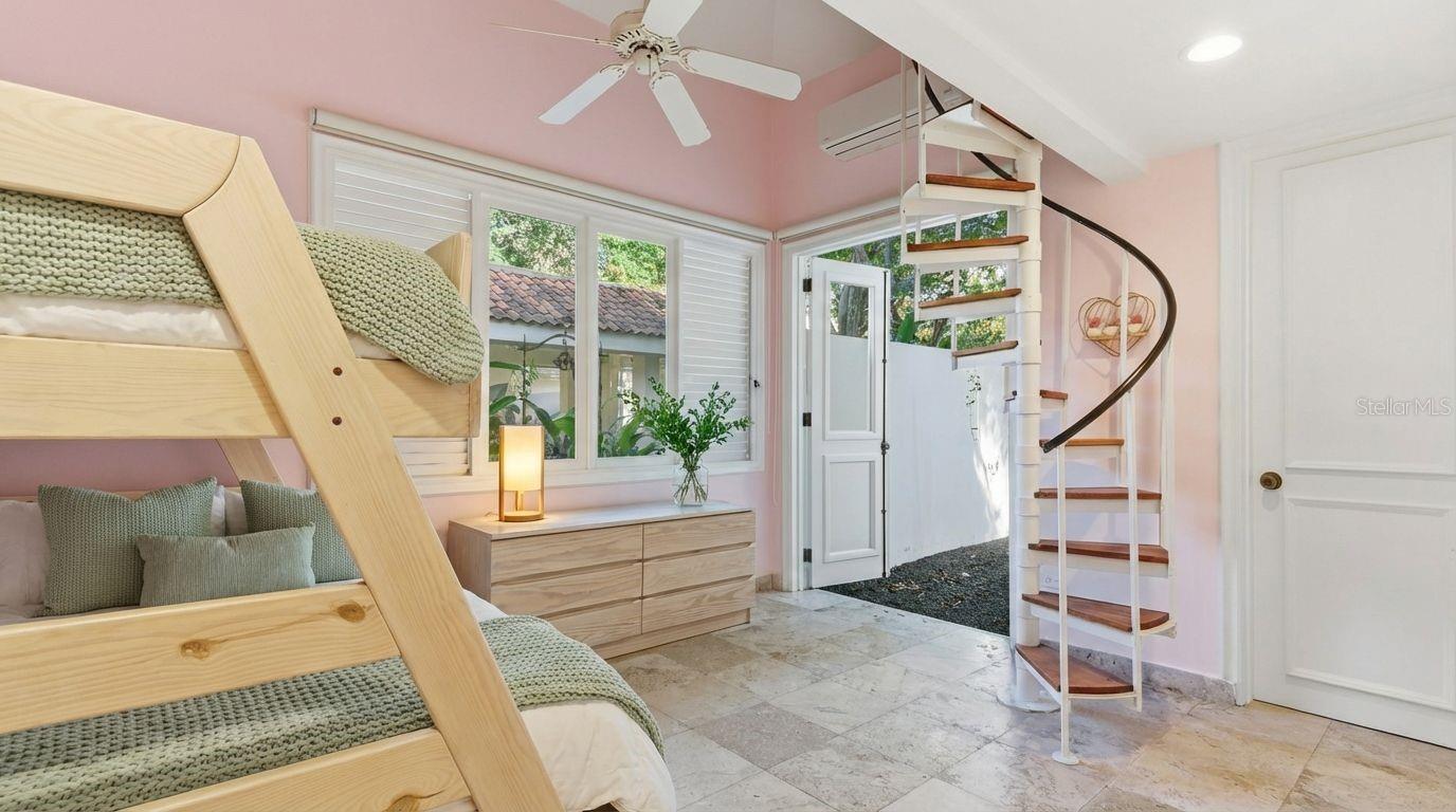 Bedroom with a wooden bunk bed and a white spiral staircase.