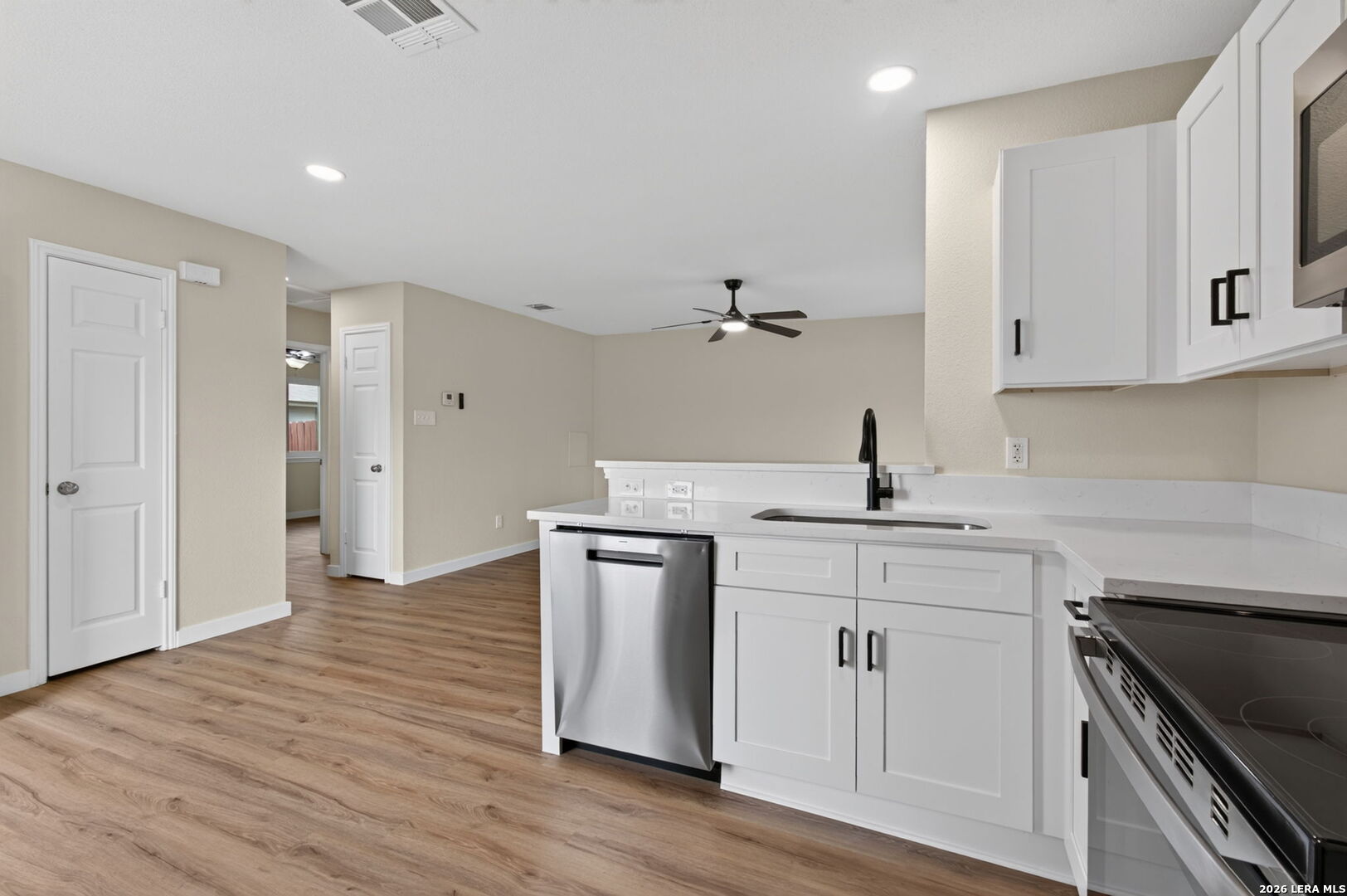 Unfurnished kitchen with white cabinets, stainless steel appliances, and wood-look flooring.
