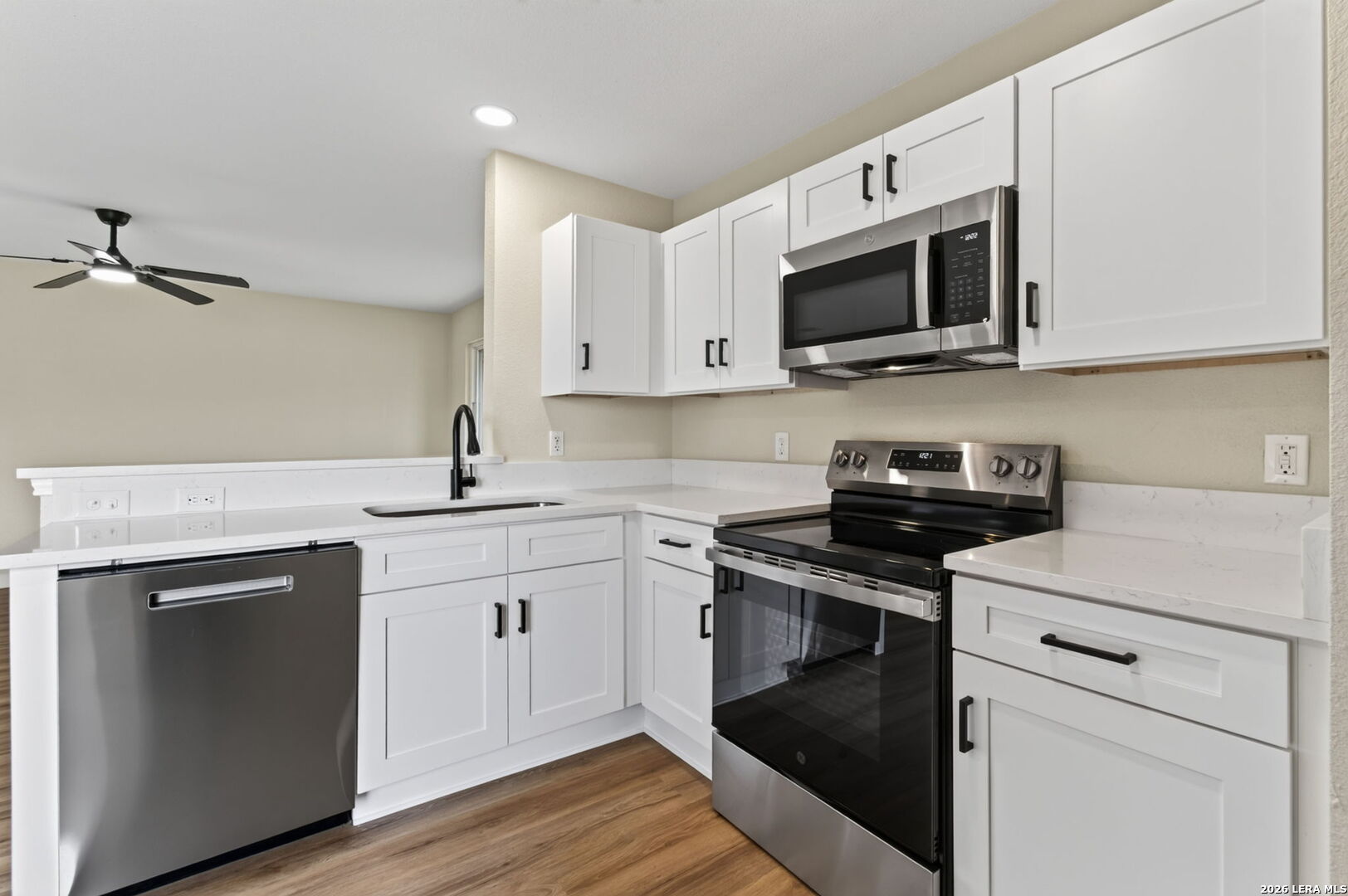 Kitchen with white cabinets, stainless steel appliances, and wood-look flooring.