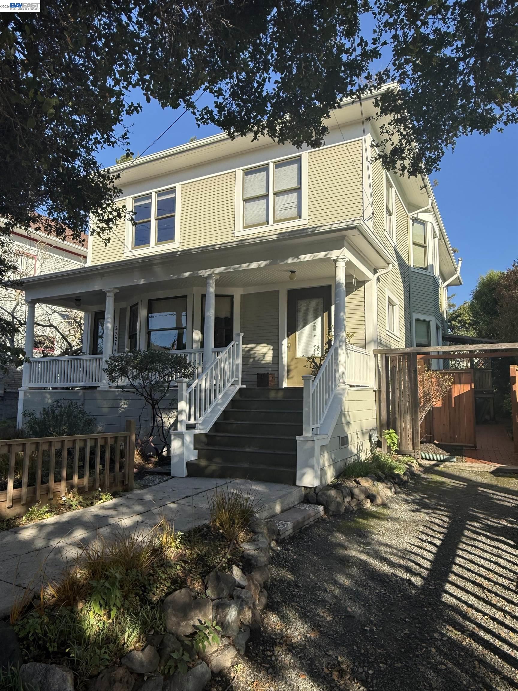 Two-story yellow house with a covered porch, broad front steps, and a stone-edged garden path.