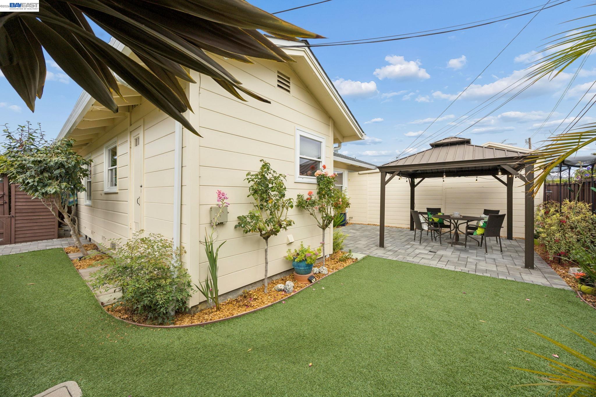 Backyard with a green lawn and a gazebo-covered patio with outdoor dining furniture.