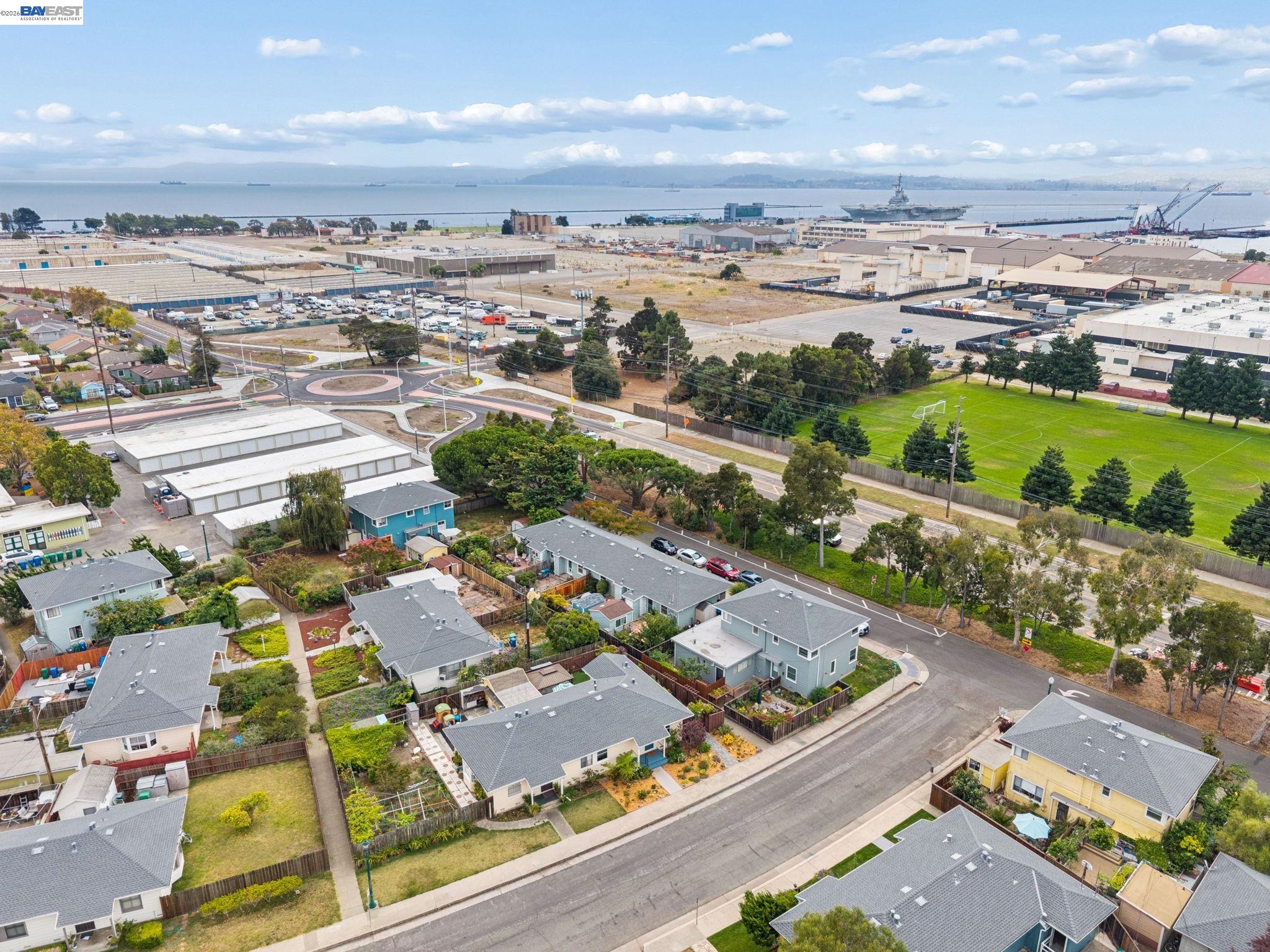 Aerial neighborhood view with a soccer field and industrial waterfront beside the bay.