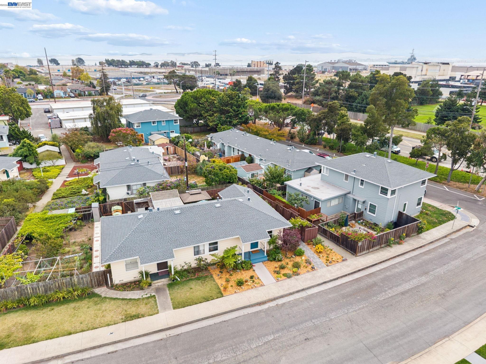 Aerial view of neighborhood homes, with a cream-colored house and blue porch beside a corner street.