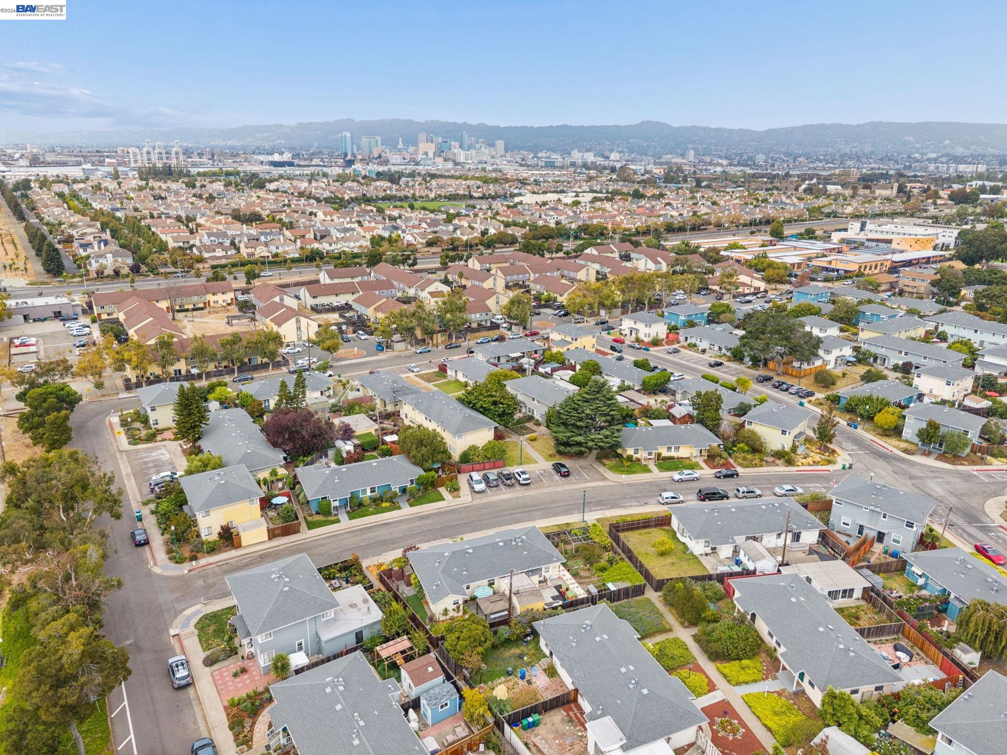Aerial view of neighborhood homes with a distant city skyline and hills.