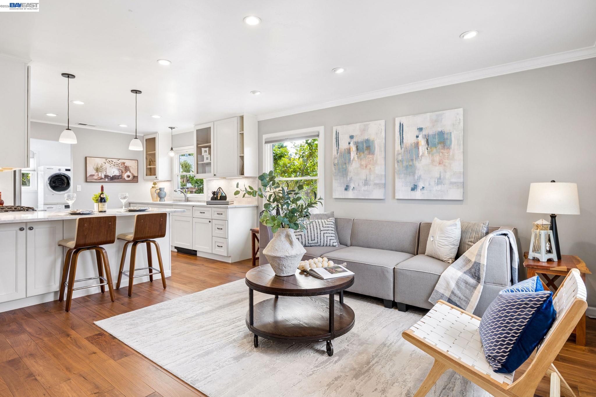 Open-plan living room and kitchen with a gray sofa, white cabinetry, and a breakfast island.