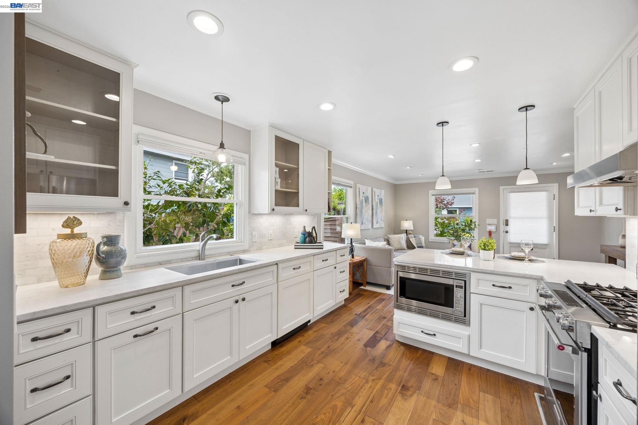 Bright kitchen with white cabinets, a large island, stainless steel range, and warm wood floors.