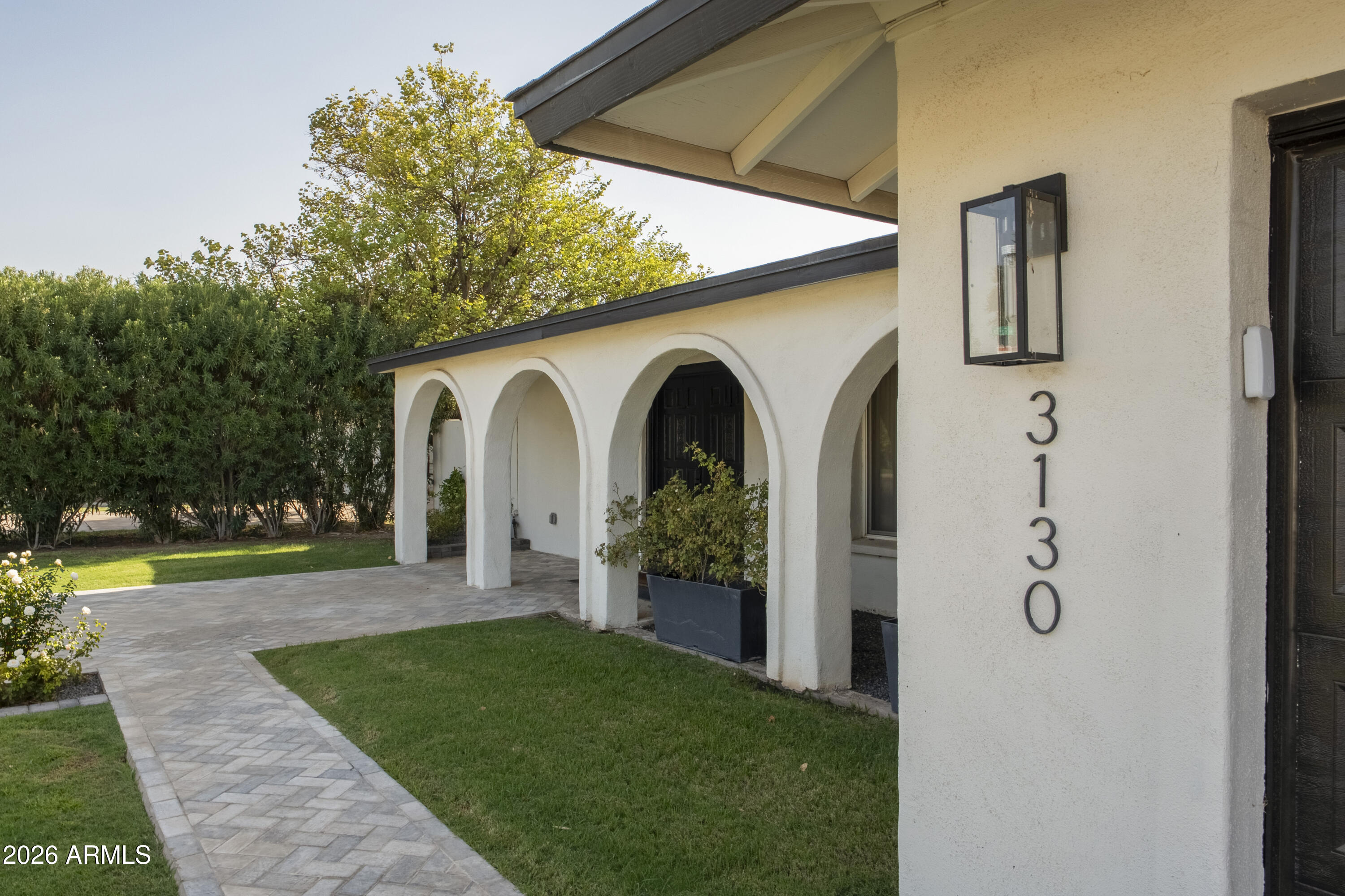 Home entrance with white stucco arches, a paved walkway, and address number 3130.