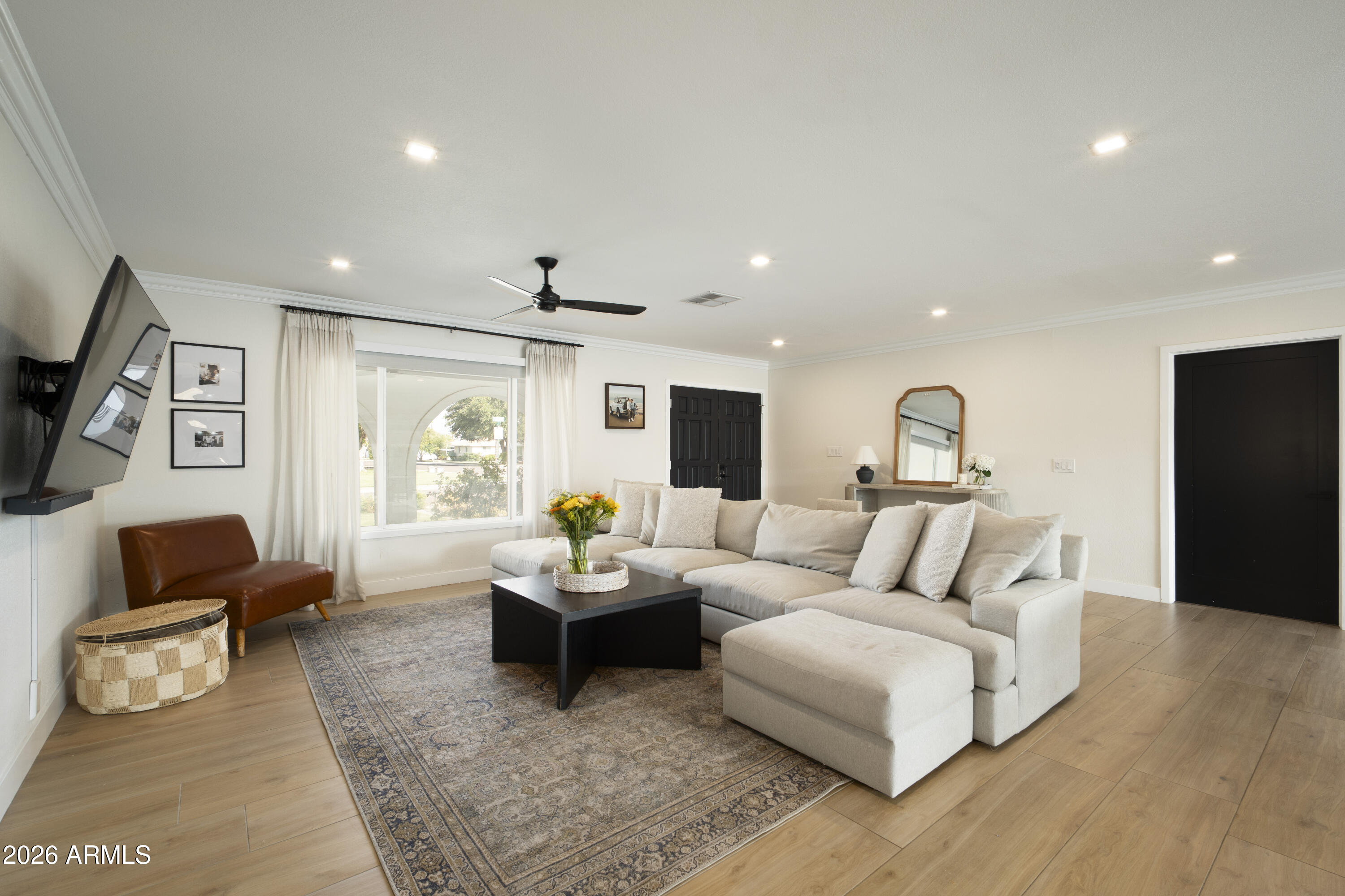 Living room with a cream sectional, patterned rug, and bright curtained window.