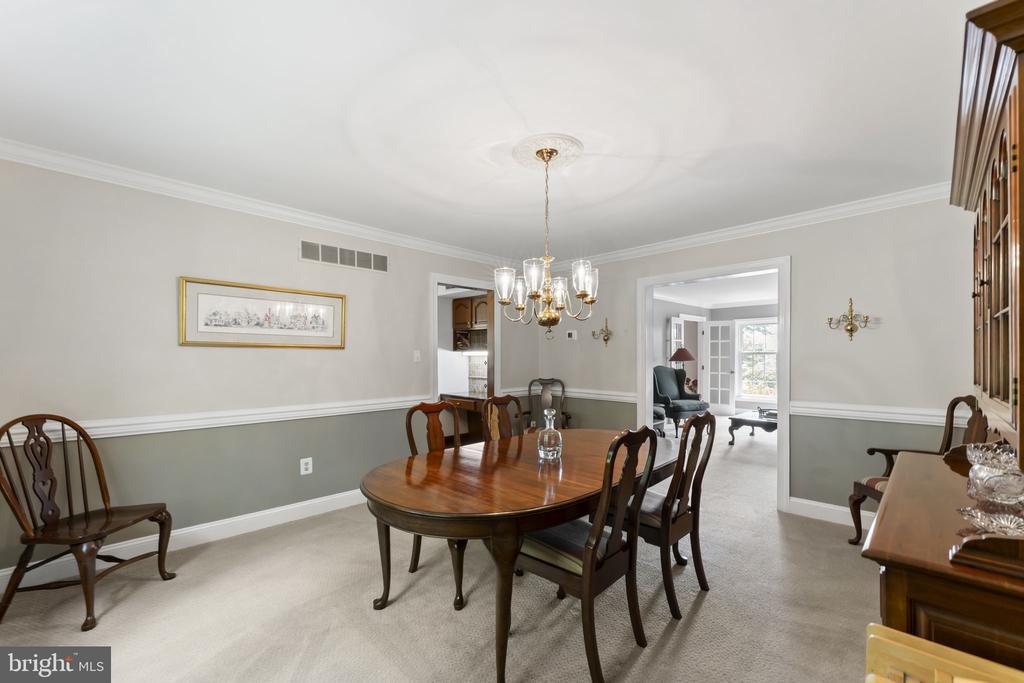 Dining room with an oval wooden table, chandelier, and doorway to a bright sitting room.
