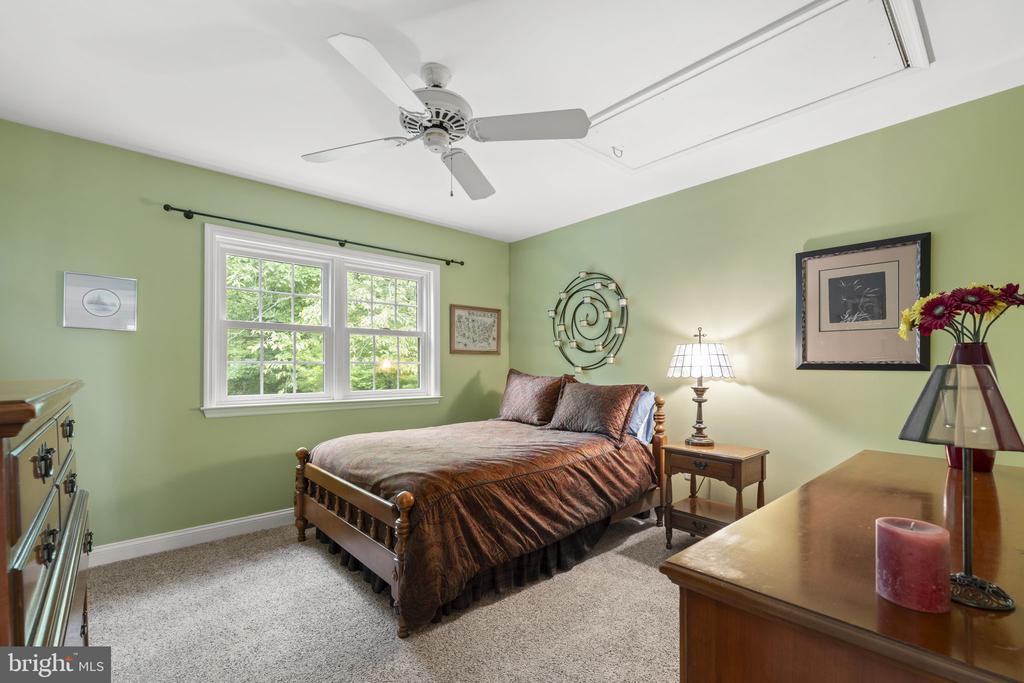 Furnished bedroom with green walls, a wooden bed, and a large double window.