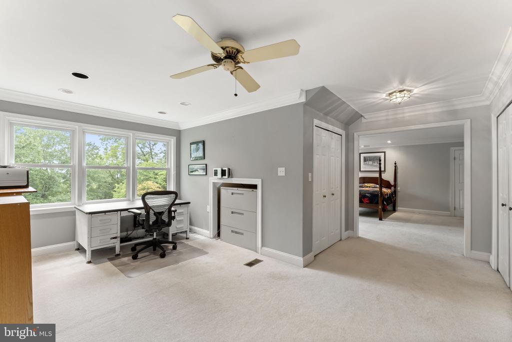 Finished room with a desk beneath three large windows and an adjoining bedroom.