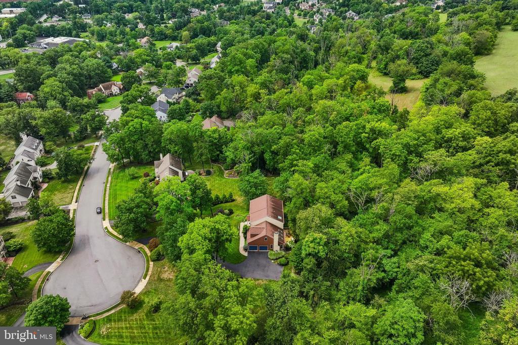Aerial view of a home beside a wooded cul-de-sac in a leafy neighborhood.