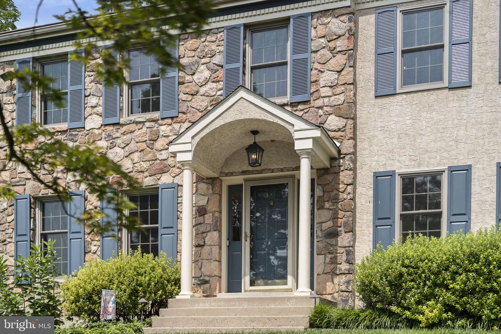 Two-story stone-and-stucco house with blue shutters and a covered front entry.