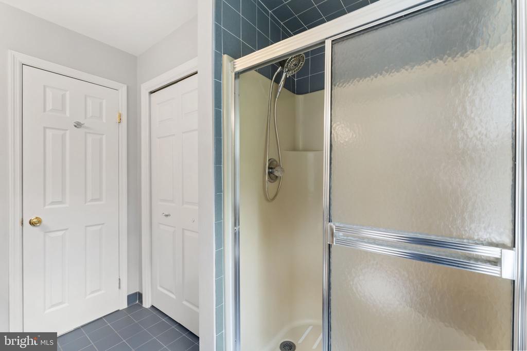 Bathroom shower with frosted sliding glass doors and blue-gray tiled floor.