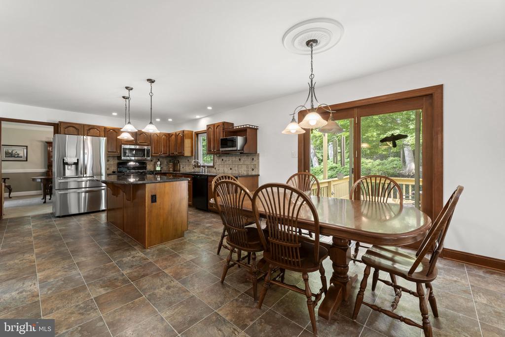 Kitchen and dining area with a wood island, stainless appliances, and a dining table beside deck doors.