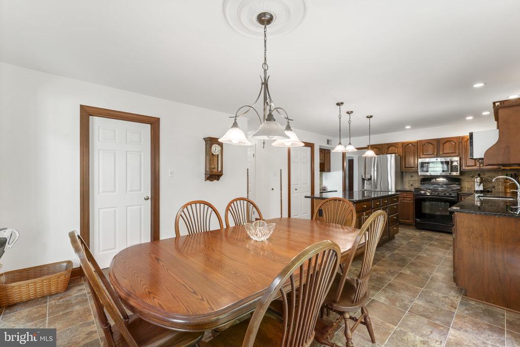 Dining area with a large wooden table beside a kitchen with warm wood cabinets and stainless steel appliances.
