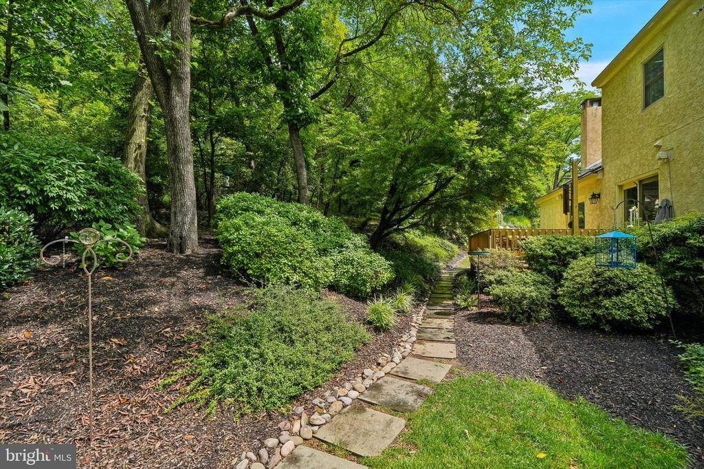 Wooded landscaped yard with a stepping-stone path leading to the home’s deck.