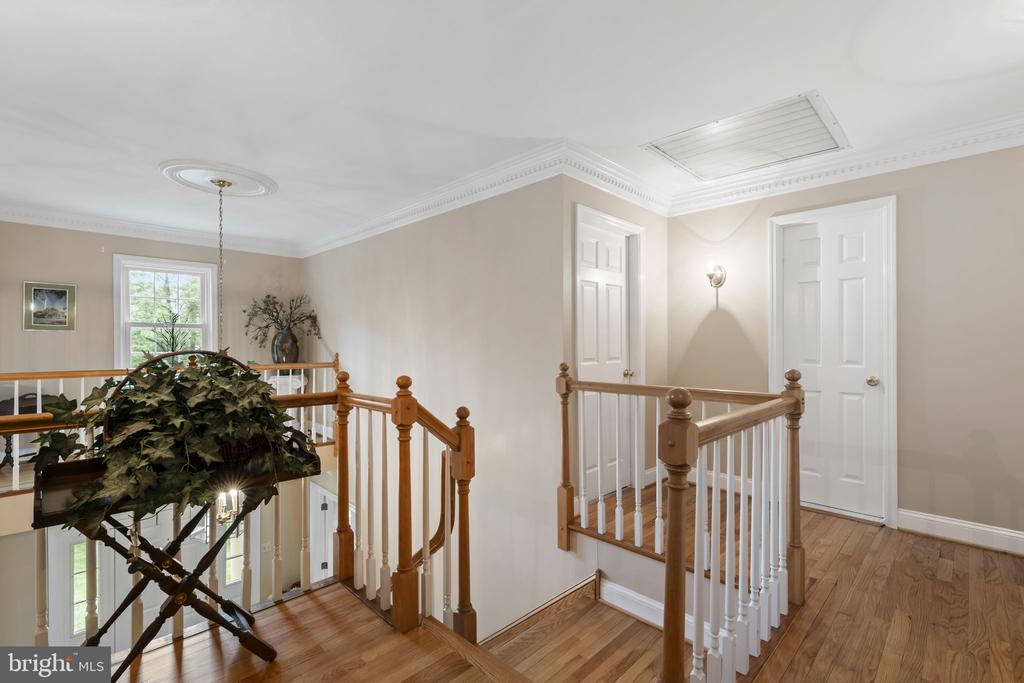 Upstairs landing with hardwood floors, paneled doors, and a wood-and-white stair railing.