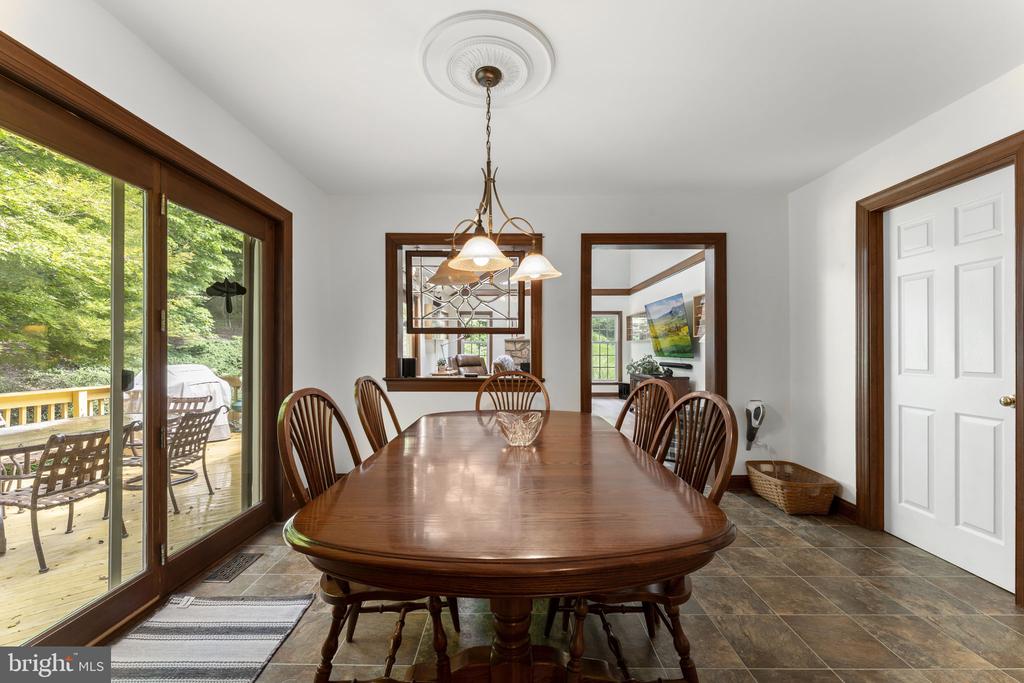 Dining room with a long wooden table, spindle-back chairs, and sliding glass doors to a deck.