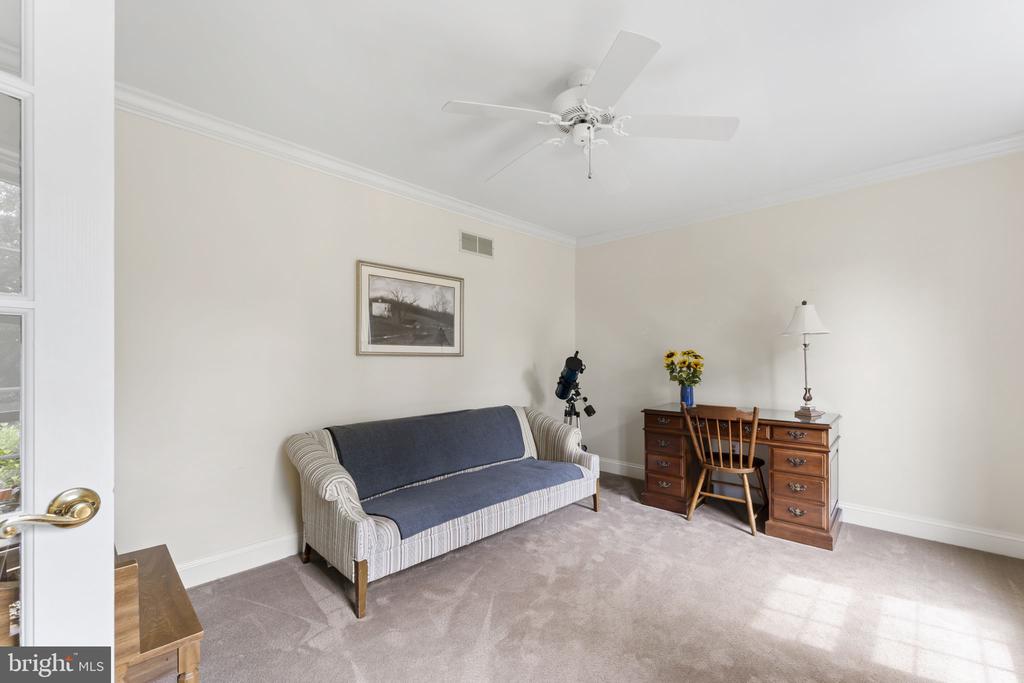 Furnished sitting room with a blue-covered sofa, wooden desk, and telescope.