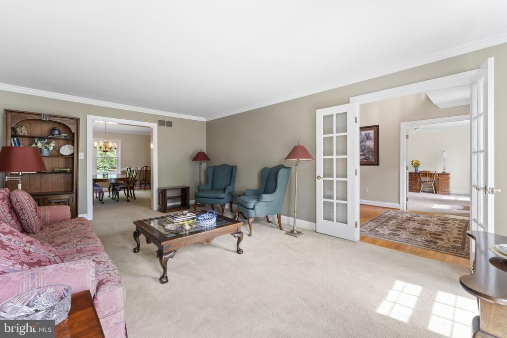 Living room with a pink patterned sofa, blue armchairs, and open French doors.