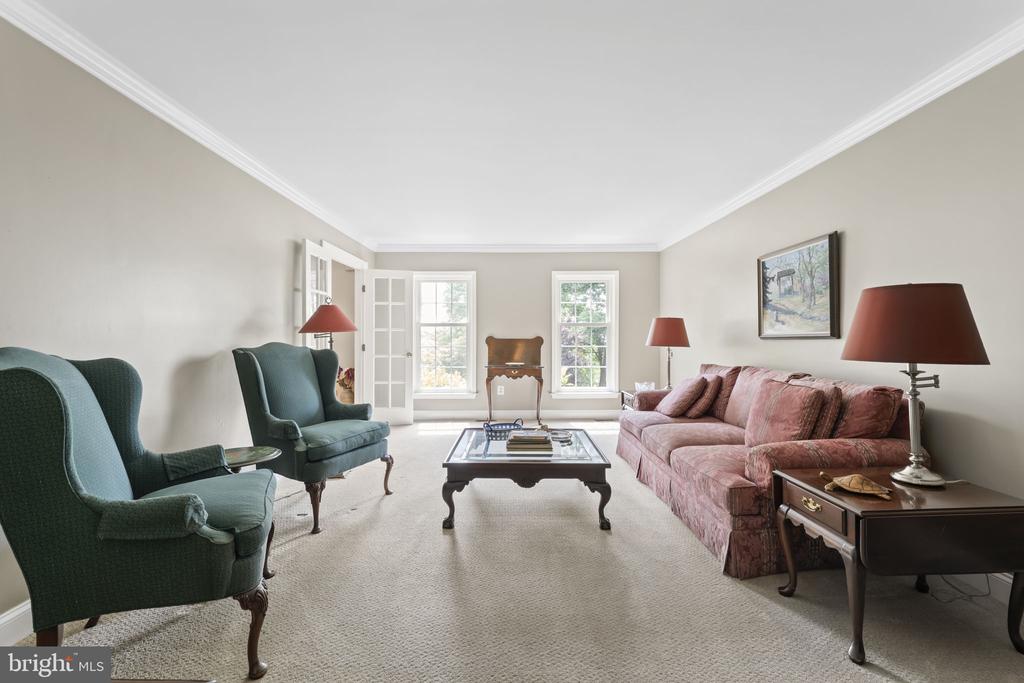 Living room with teal armchairs, a rose-colored sofa, and tall windows.